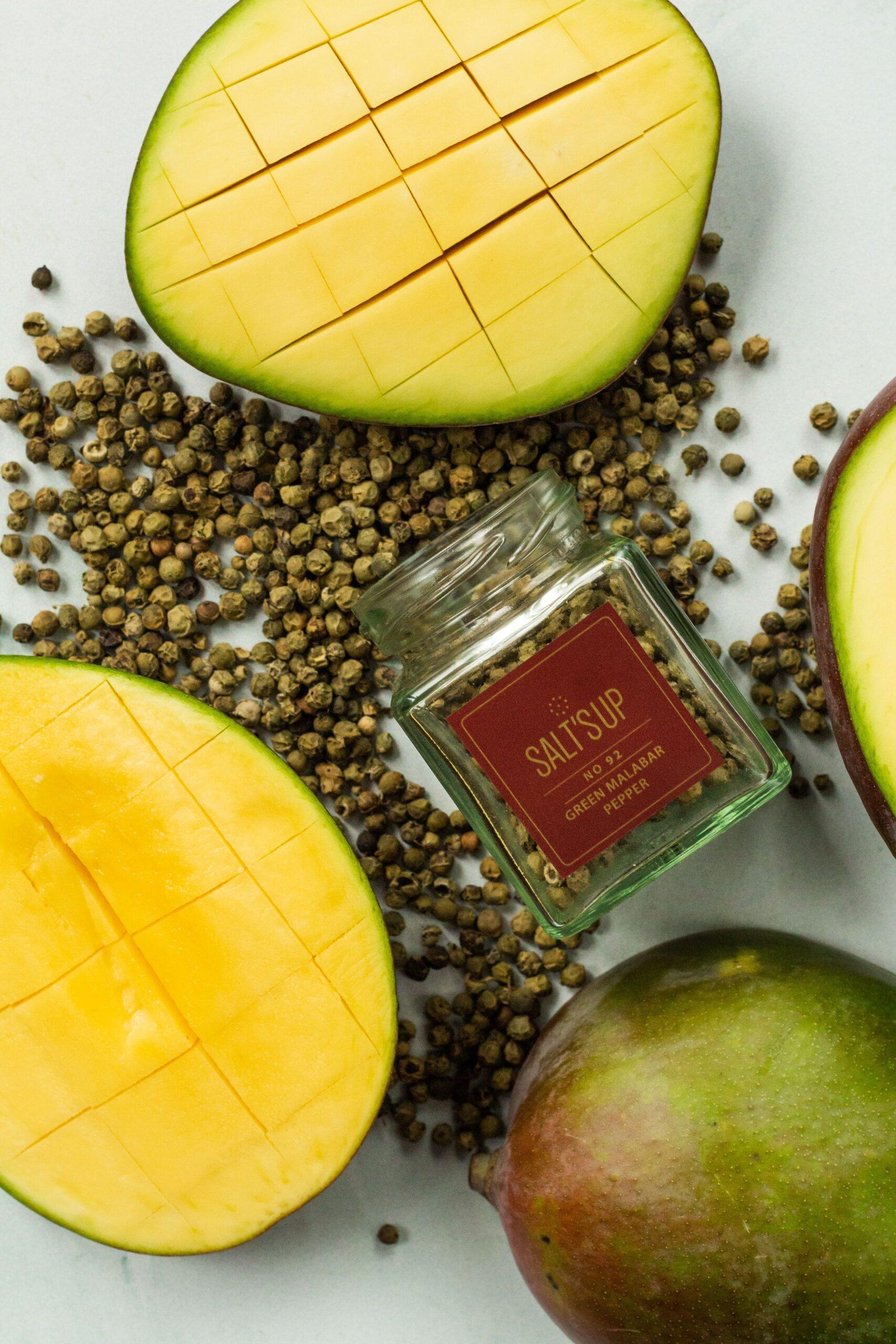 A glass jar of Malabar Green Pepper showcasing vibrant green peppercorns, sourced from Kerala, India.