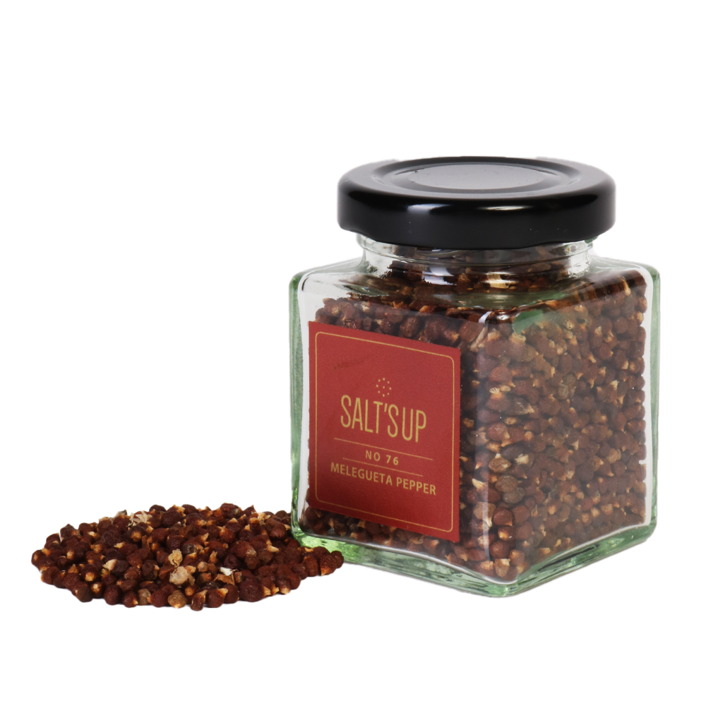 A glass jar filled with Melegueta peppercorns, showcasing their unique shape and color, with a background of spices and herbs.