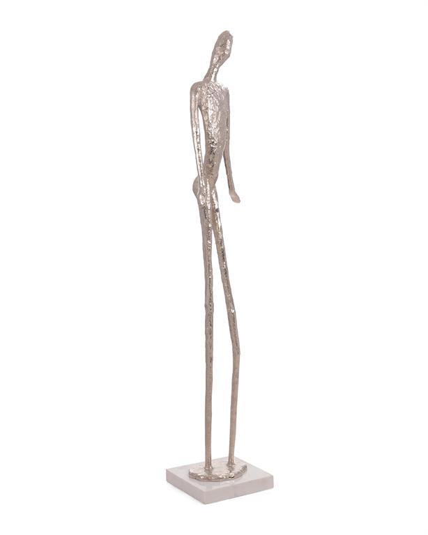 A tall Nickel Figure Three Sculpture on a white marble base, showcasing a sleek and modern design.