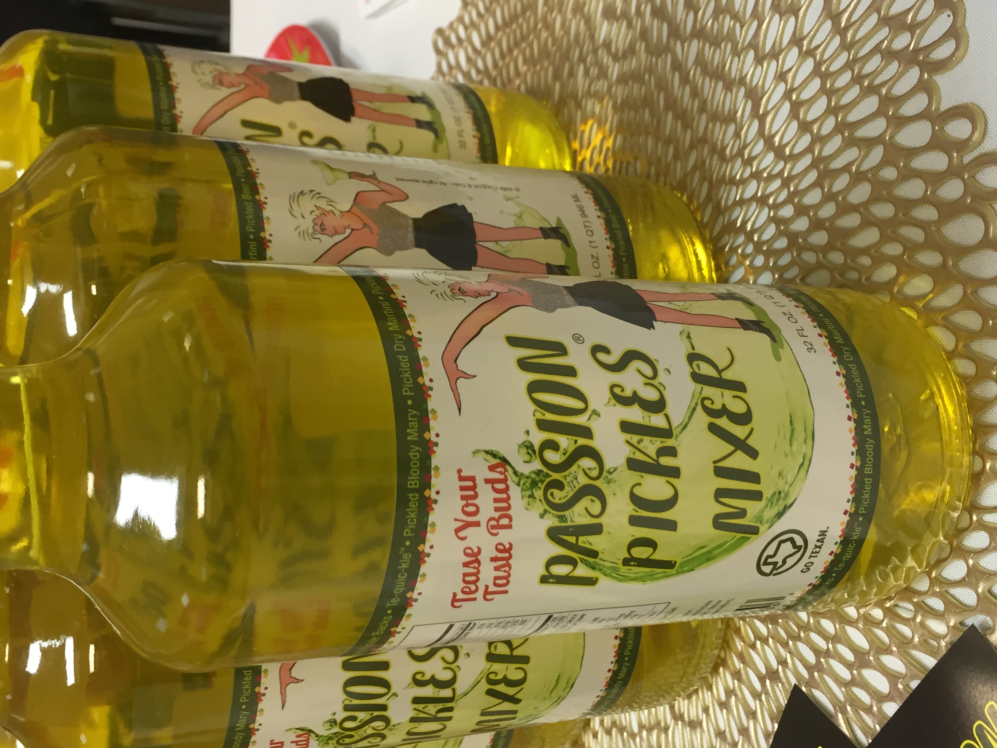 A bottle of PASSION PICKLES® MIXER showcasing its vibrant yellow color and artisan label, perfect for enhancing cocktails and dishes.