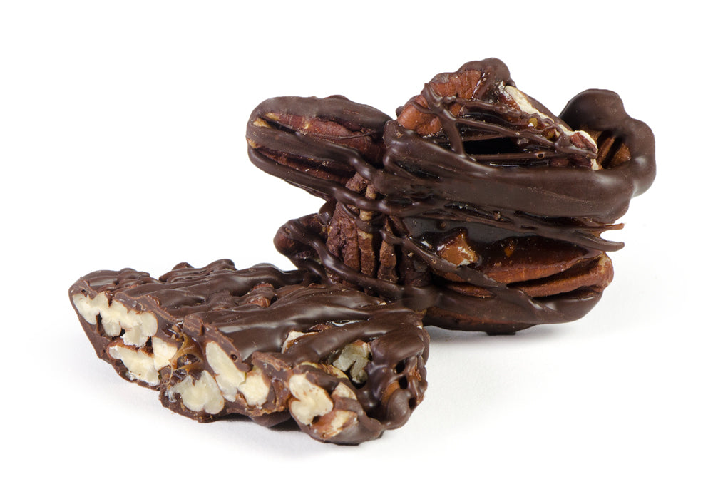 A close-up of delicious pecan patties coated in rich chocolate, showcasing their nutty texture and appealing appearance.