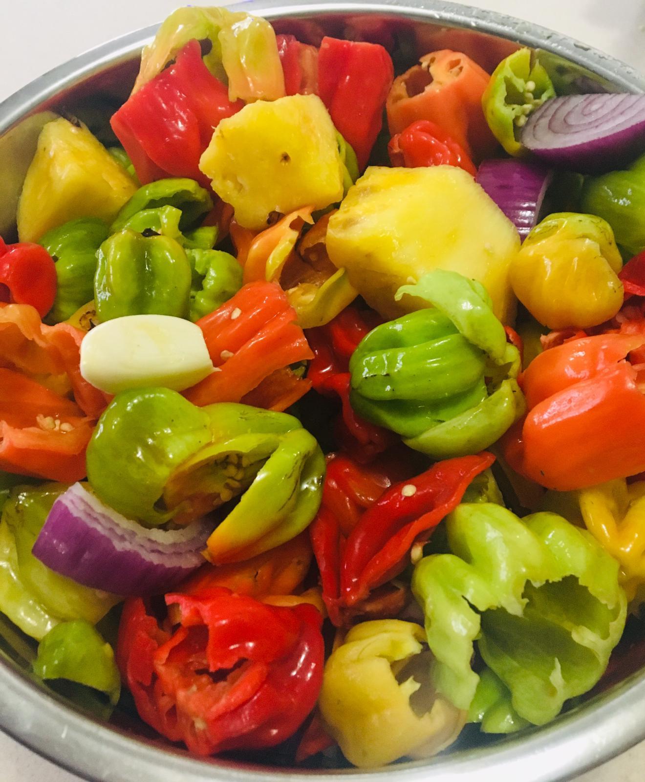 A bottle of Pineapple Hot Sauce featuring fresh pineapples and scotch bonnet peppers, showcasing its vibrant color and natural ingredients.