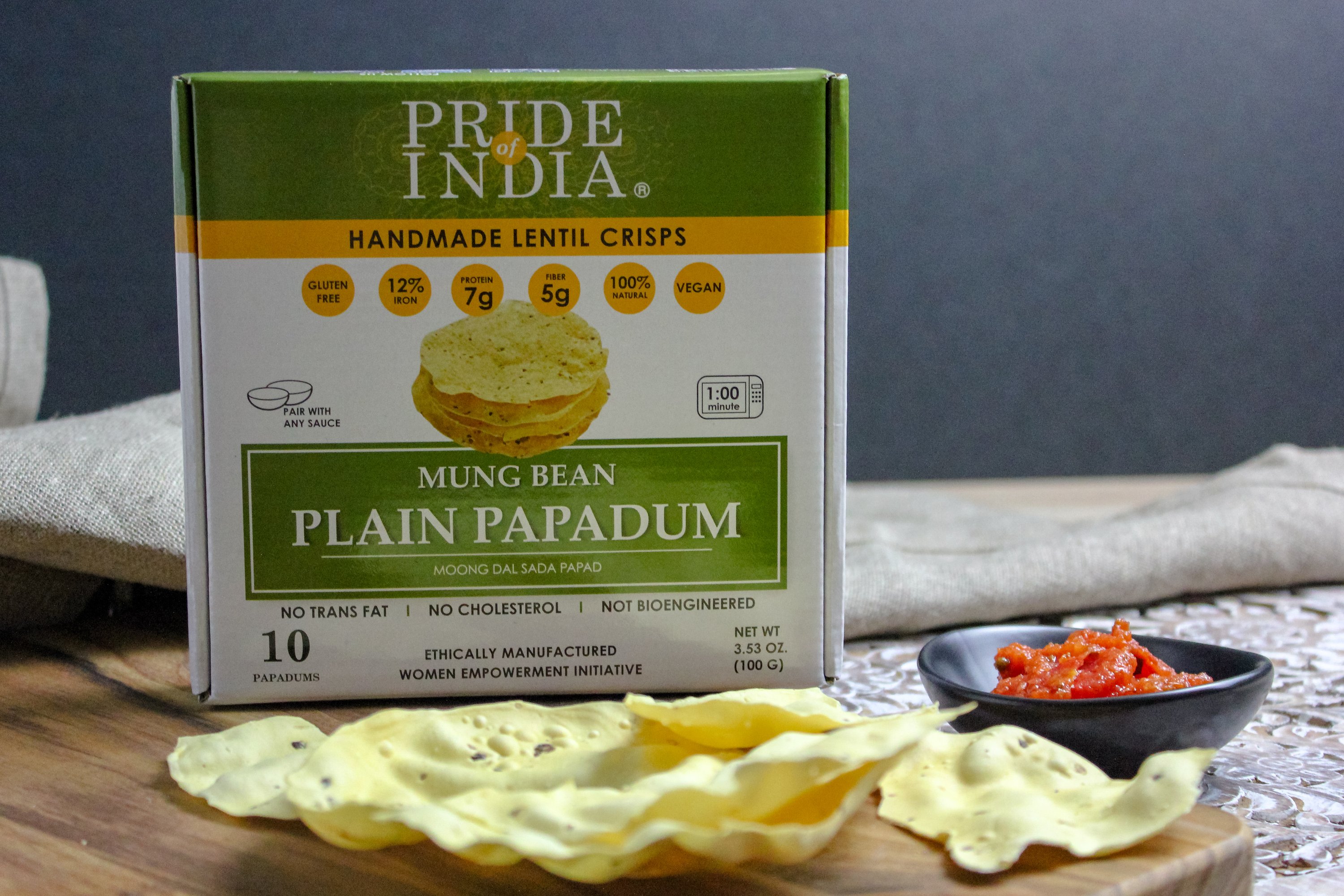 A pack of Plain Mung Bean Sada Papadum, showcasing the lentil crisps with a rustic background, highlighting their handmade quality.