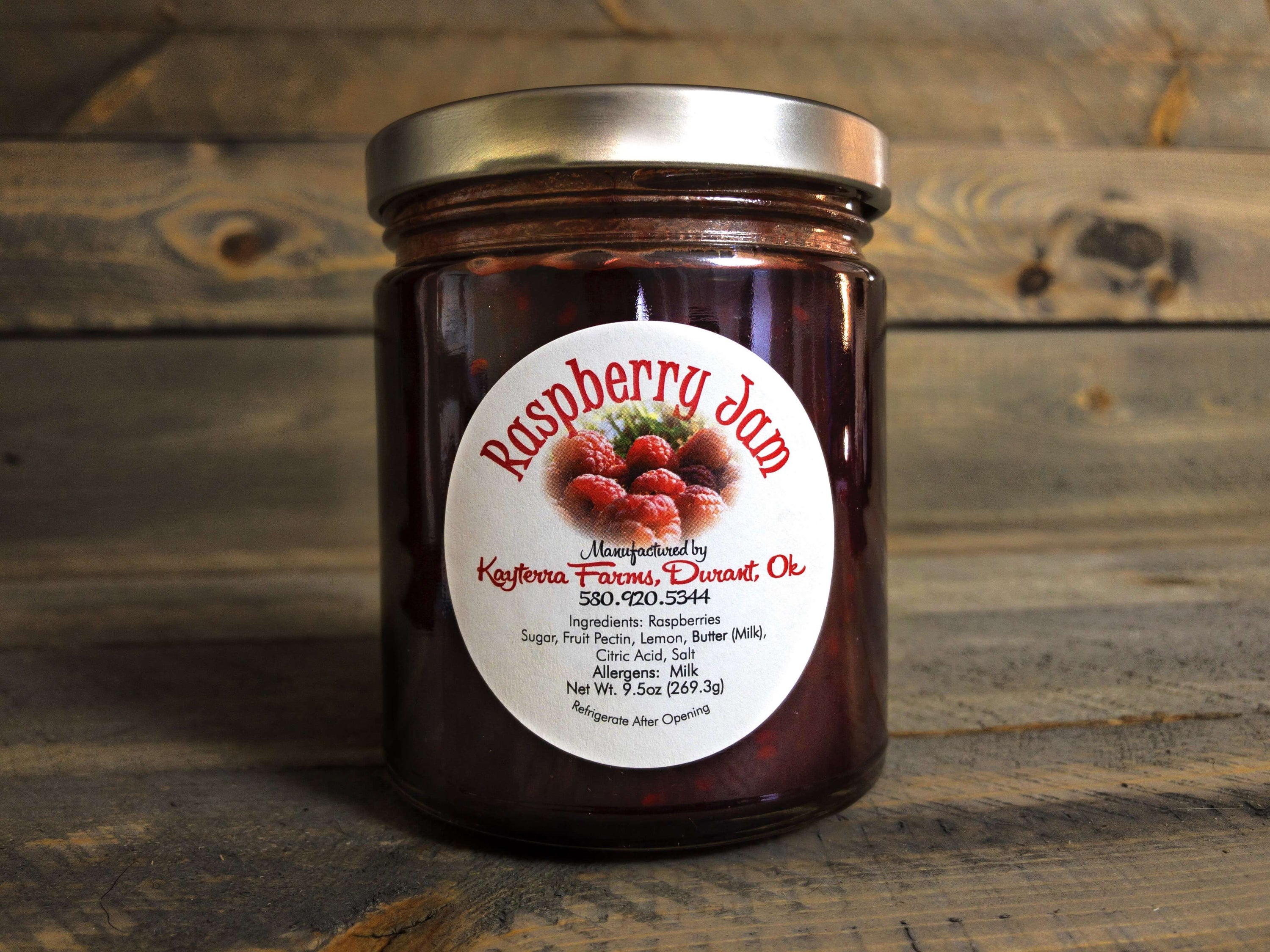 A jar of Raspberry Jam filled with bright red raspberries, showcasing its vibrant color and texture, perfect for spreading or baking.