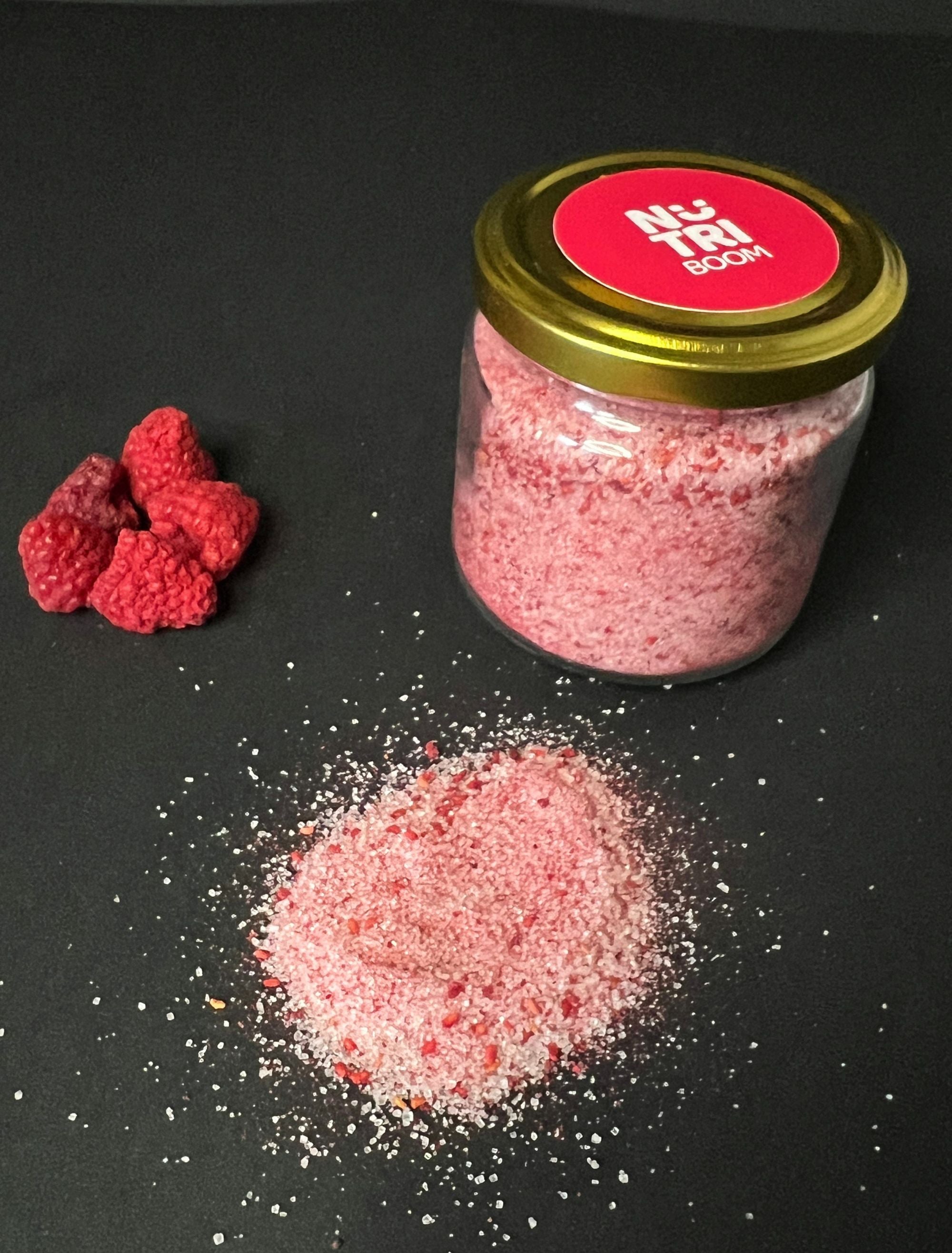 A glass jar filled with vibrant raspberry sugar, showcasing its rich pink color and fine texture, perfect for enhancing desserts.