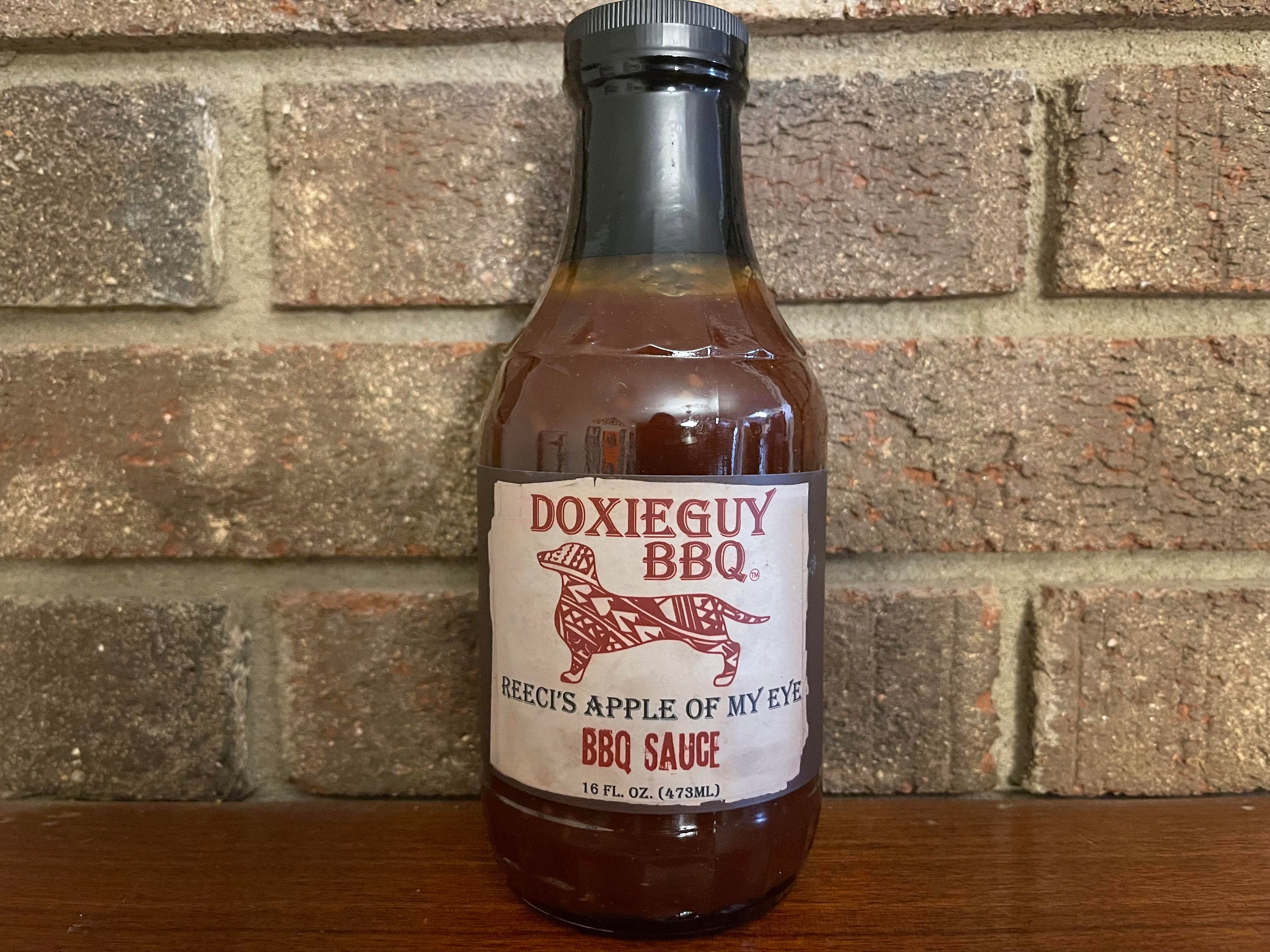 A bottle of Reeci's Apple of My Eye BBQ Sauce with a sweet apple design, showcasing its 16 oz size.