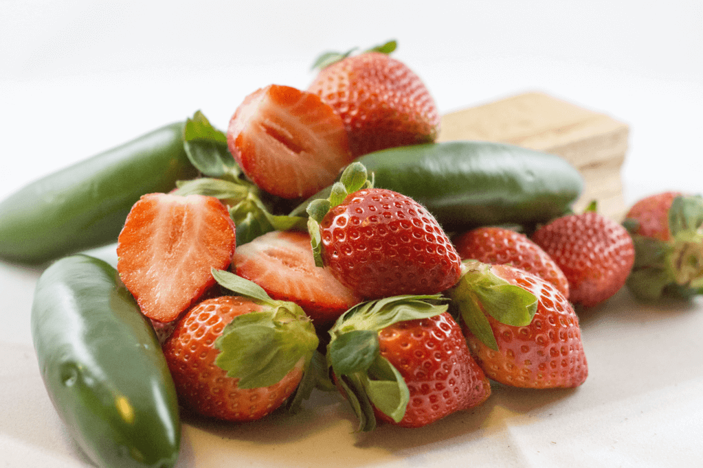 A jar of Sassy Strawberry Jalapeno jam showcasing its vibrant red color with jalapeno slices visible, perfect for adding a sweet and spicy flavor to dishes.