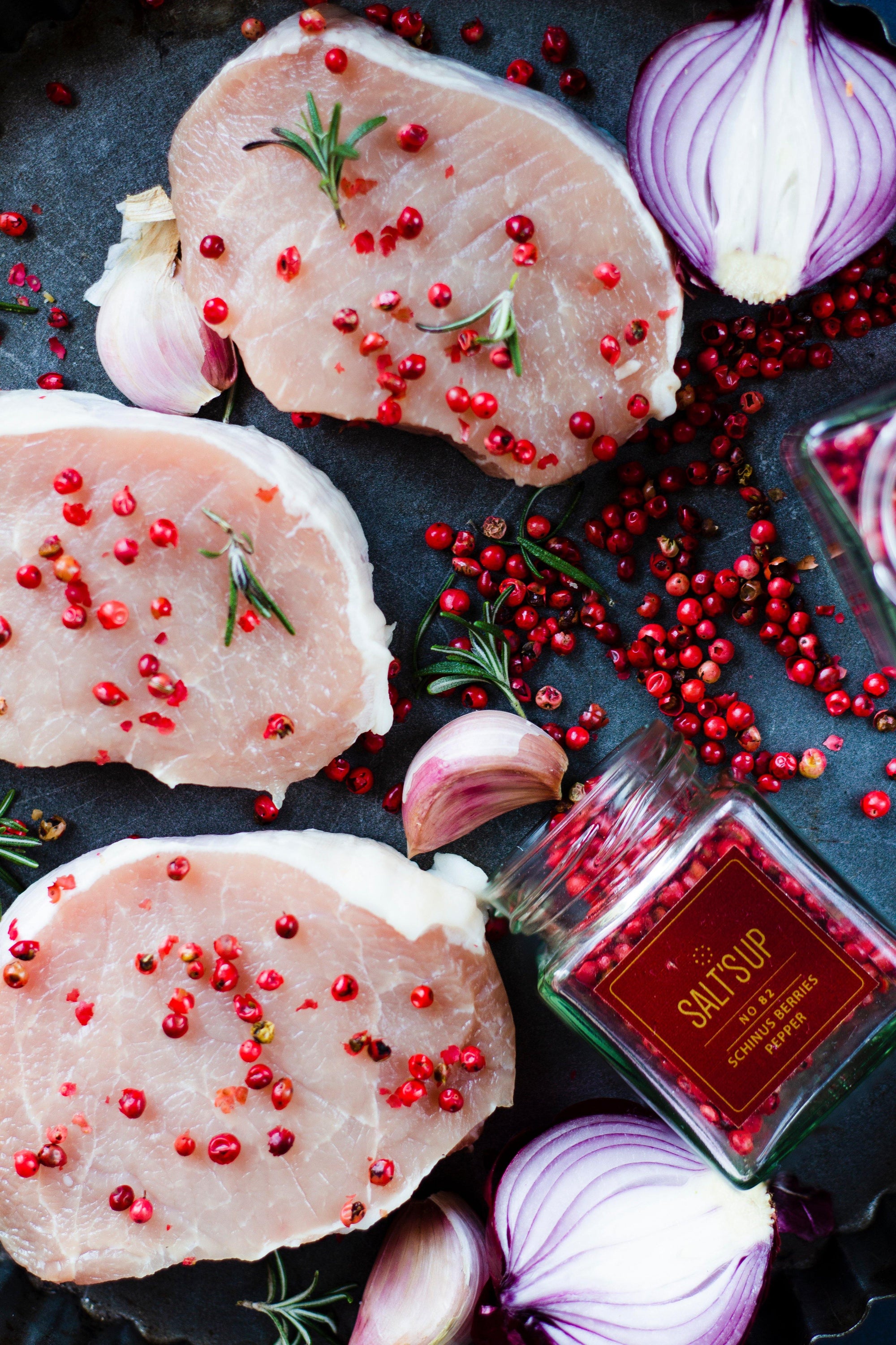 A glass jar containing SCHINUSBERRIES pepper, showcasing its vibrant pink berries, perfect for culinary use.