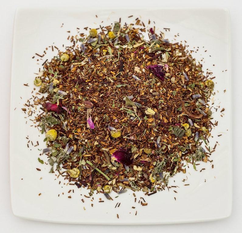 A soothing cup of Slumber Sleep Support Tea featuring lavender and chamomile, surrounded by organic ingredients like honeybush and hibiscus.