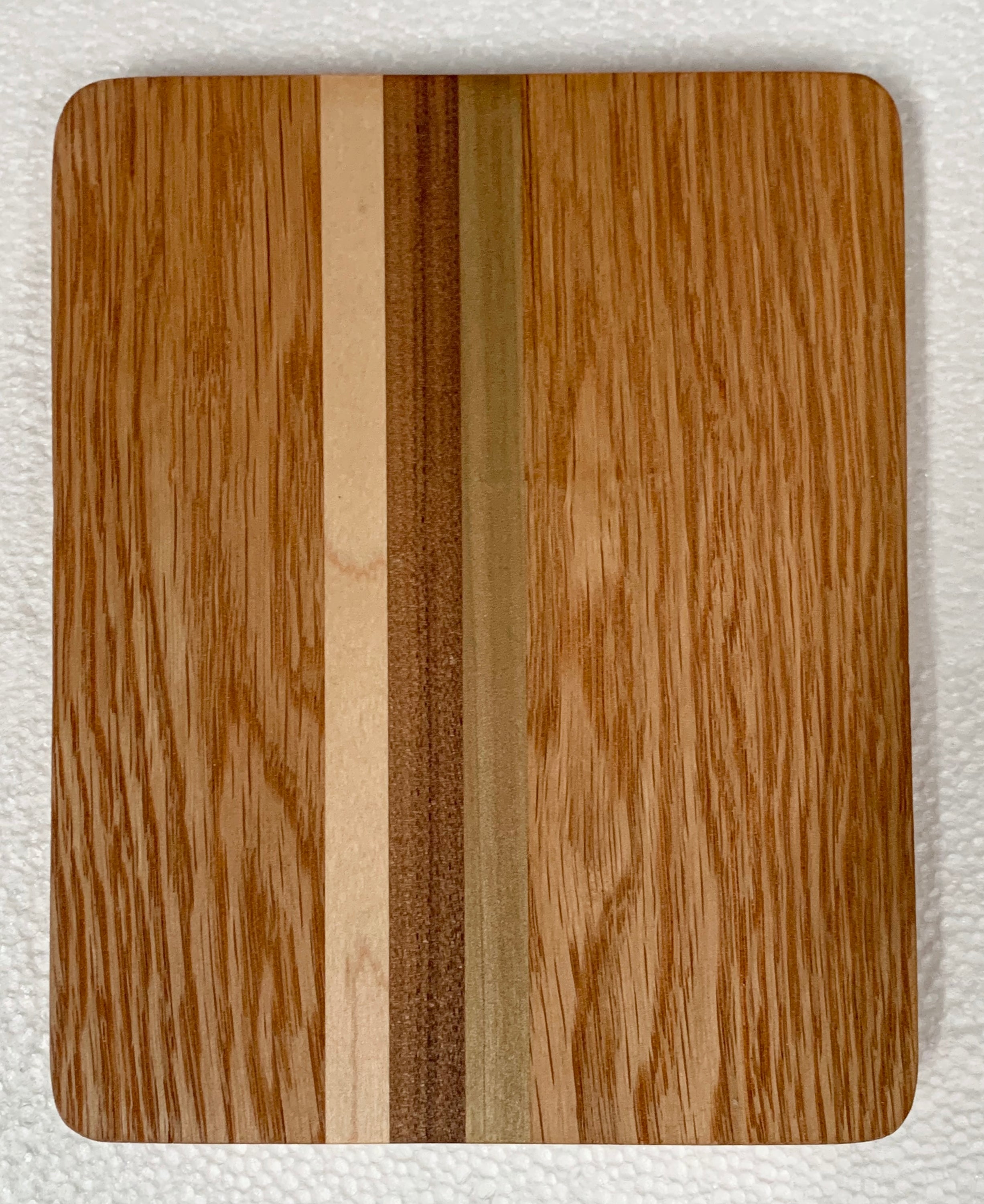 A small, multicolored wooden cutting board ideal for serving cheese and accompaniments, measuring 8.5 in x 6.5 in.