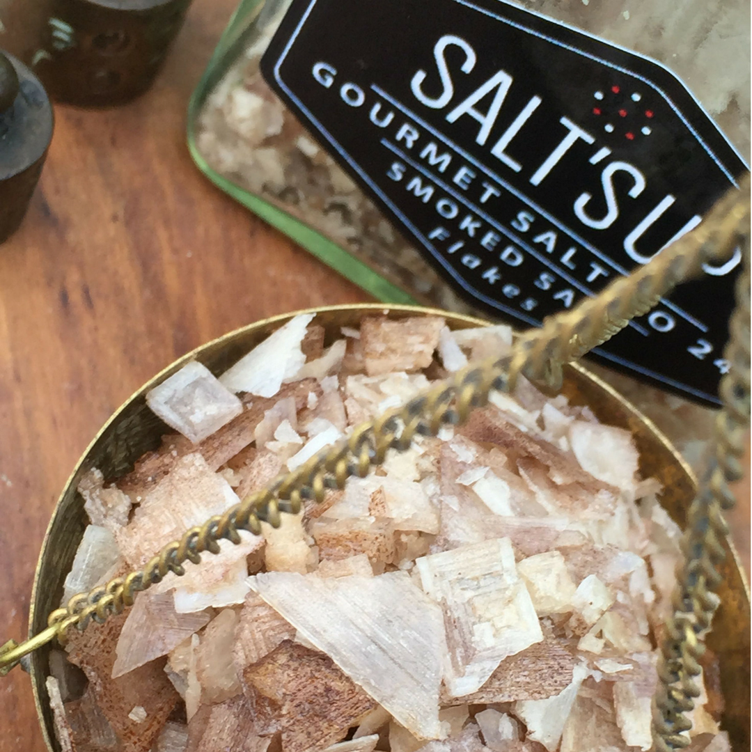 A jar of Smoked Salt 'BEECH' flakes showcasing its coarse texture and rich color, perfect for enhancing various dishes.