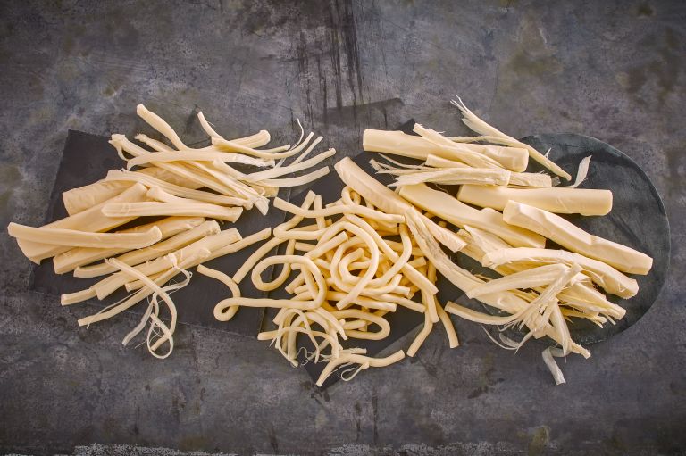 A close-up of Smoked String Cheese sticks, showcasing their semi-soft texture and hickory smoke flavor.