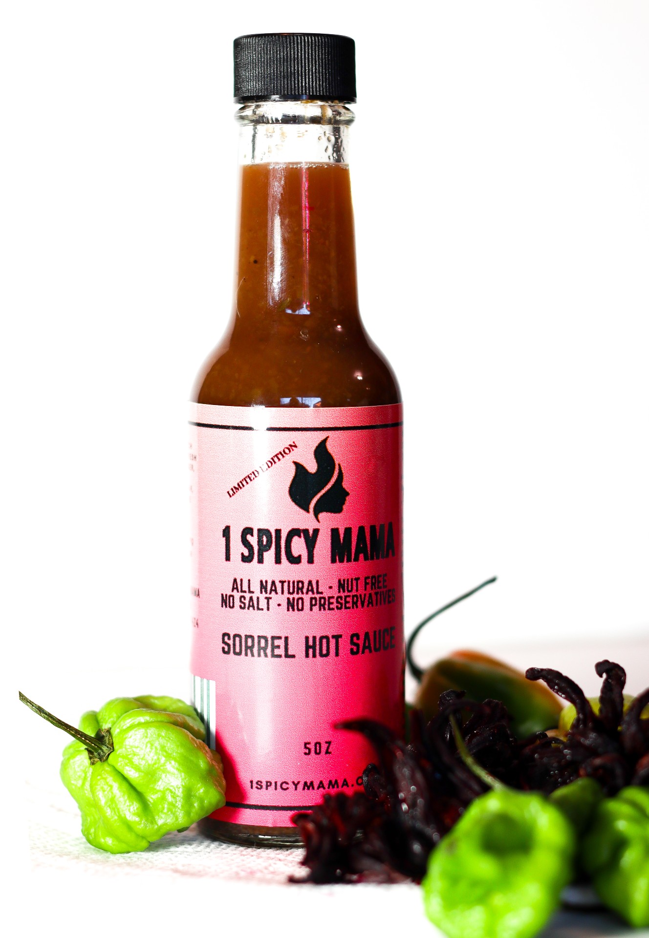 A bottle of Sorrel Hot Sauce featuring hibiscus blossoms and scotch bonnet peppers, showcasing its vibrant color and rich texture.