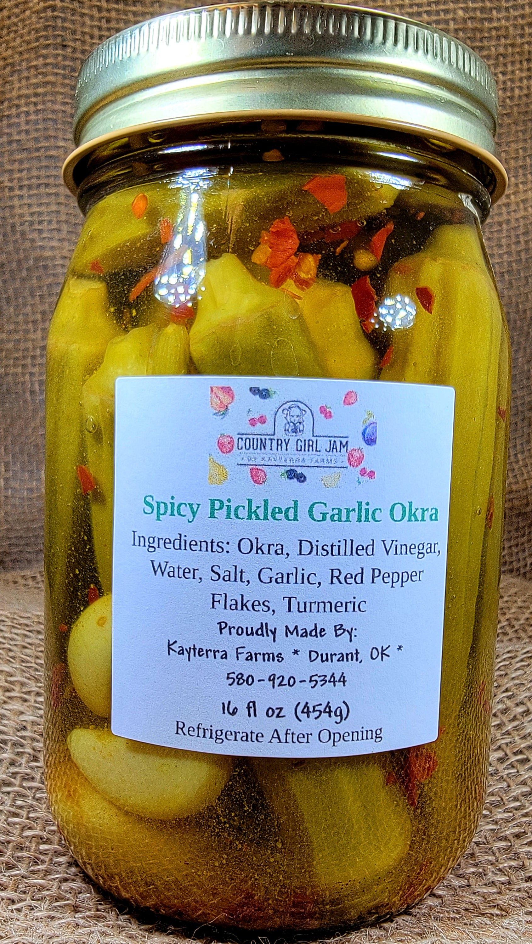 A jar of Spicy Pickled Okra showcasing vibrant green okra pods immersed in a spicy brine with spices.