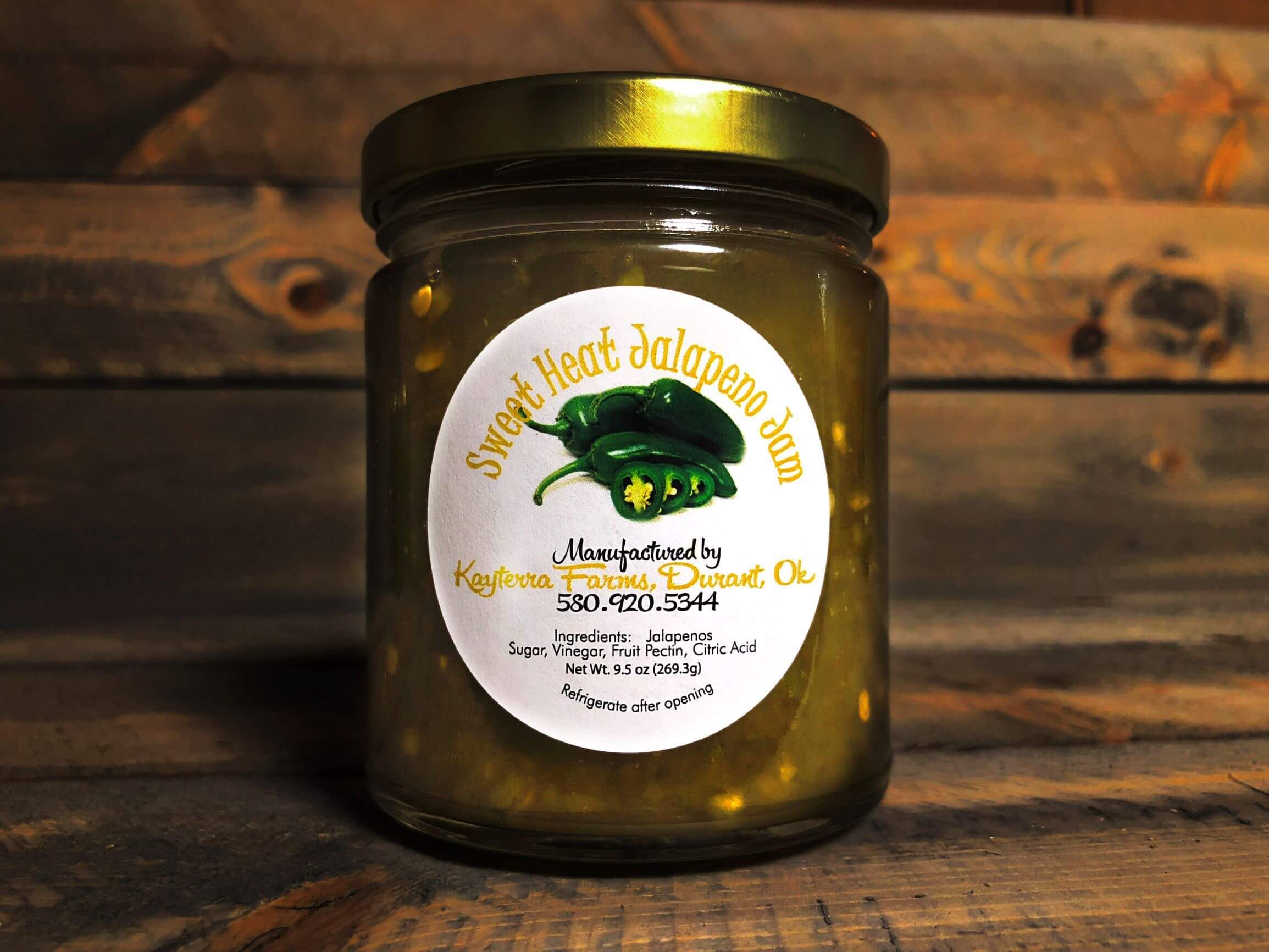 A jar of Sweet Heat Jalapeno Jam with jalapeño pieces, showcasing its vibrant color and texture.