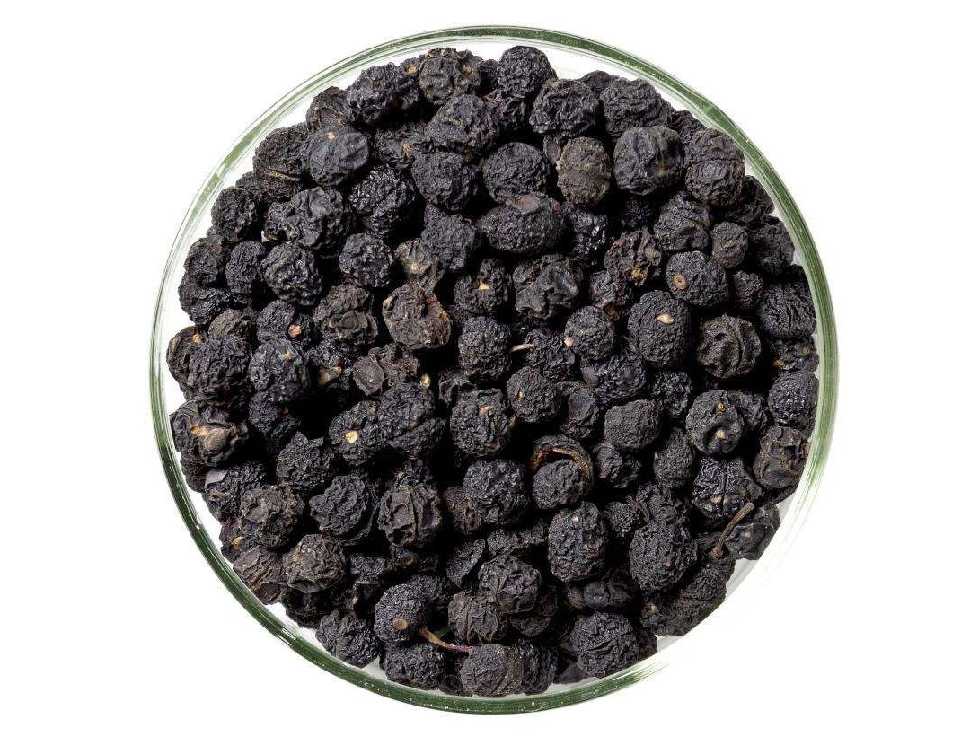 A jar of Tasmanian pepper ecopack showcasing its vibrant pink/purple hue and large berries, set against a rustic wooden background.