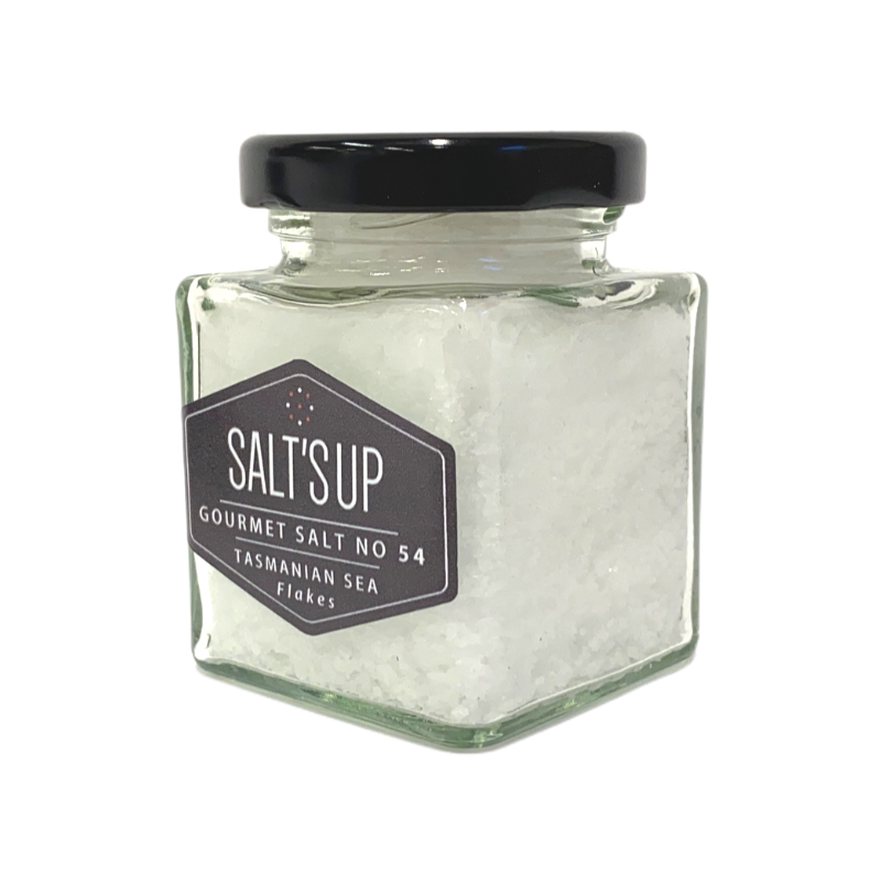 A glass jar filled with Tasmanian sea salt flakes, showcasing their flaky texture and purity.