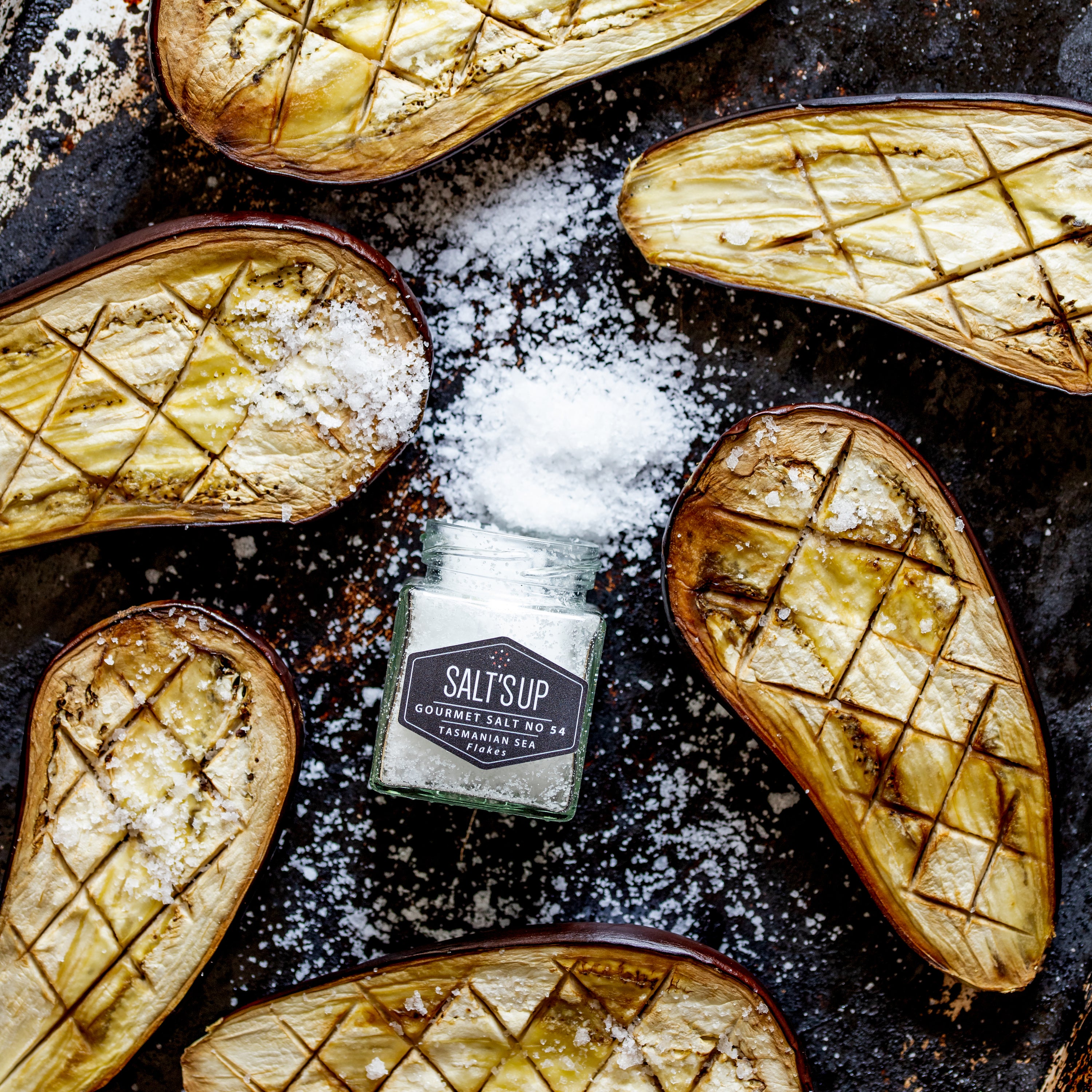 A glass jar filled with Tasmanian sea salt flakes, showcasing their flaky texture and purity.