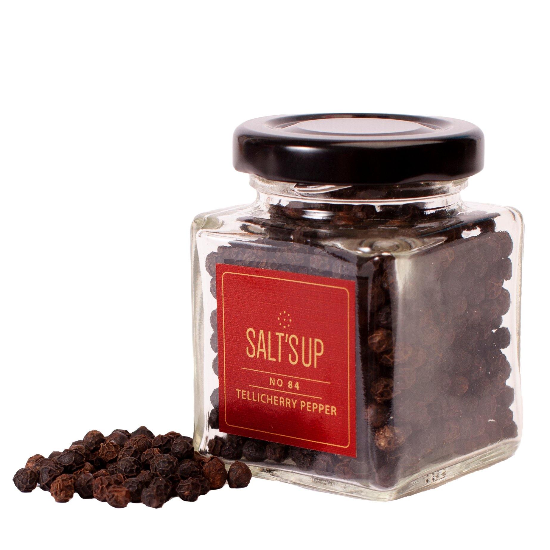 A glass jar containing high-quality Tellicherry peppercorns, showcasing their bold size and rich color.