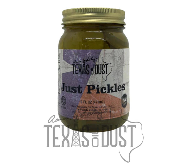 A bottle of Texas Oil Dust Just Pickles marinade with a rustic background, showcasing its label and rich color.