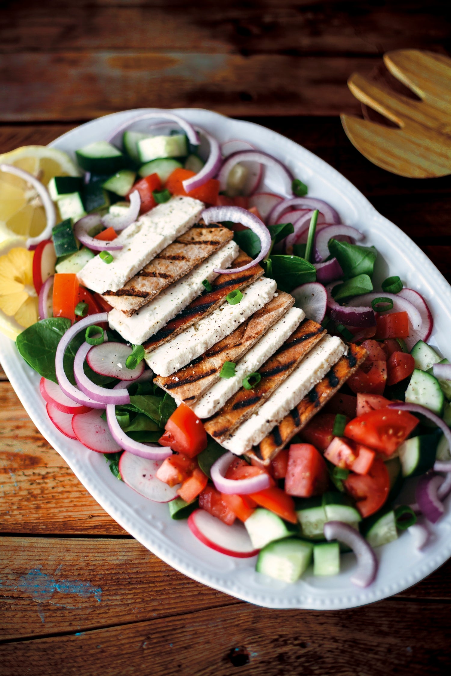 A block of Tomato Basil Feta cheese with fresh tomatoes and basil leaves, showcasing its vibrant colors and textures.