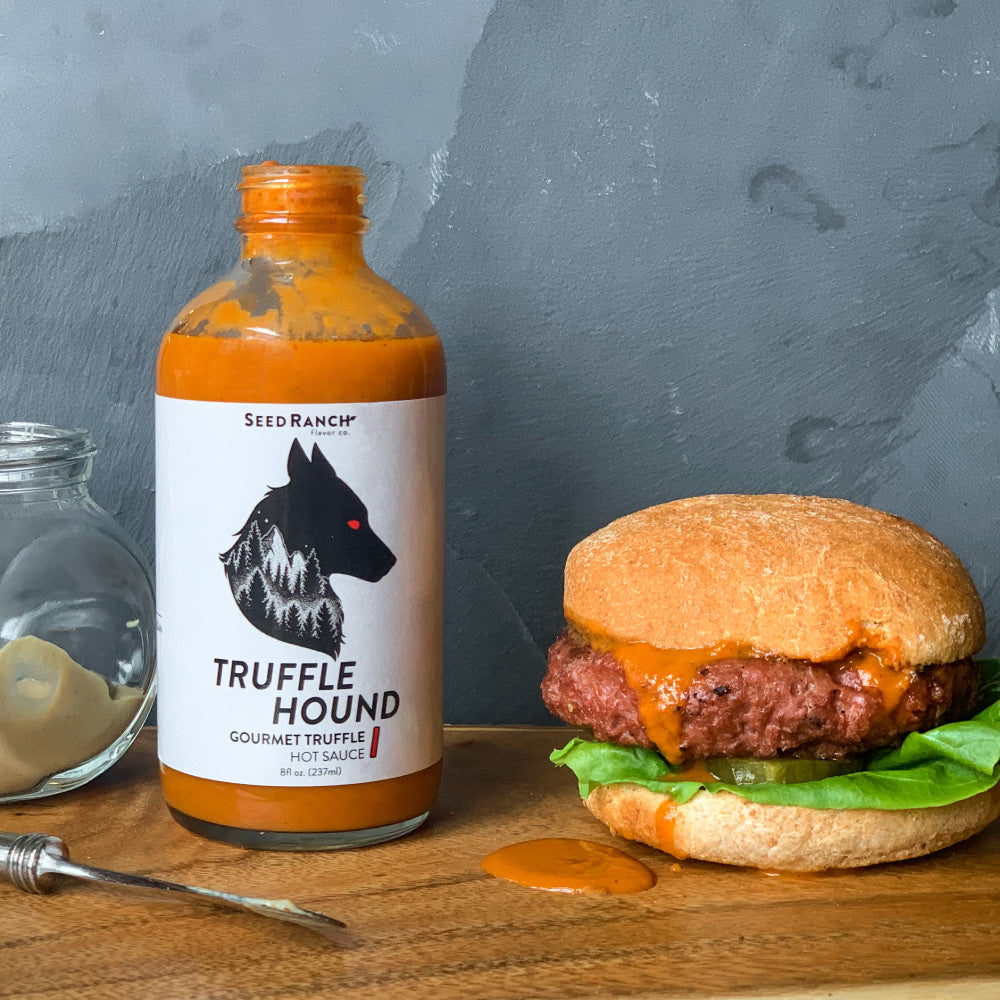 A bottle of Truffle Hound gourmet hot sauce featuring real summer truffles and organic chili peppers, elegantly designed for culinary enthusiasts.