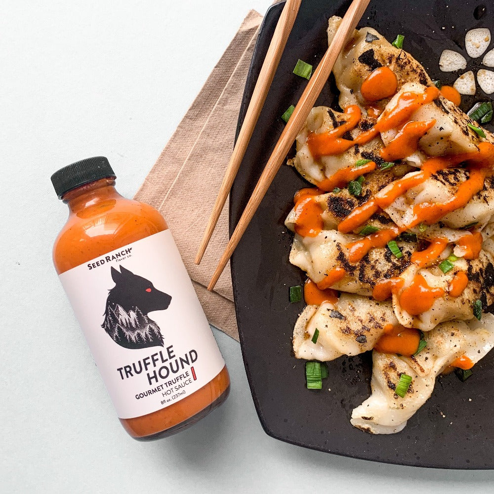 A bottle of Truffle Hound gourmet hot sauce featuring real summer truffles and organic chili peppers, elegantly designed for culinary enthusiasts.