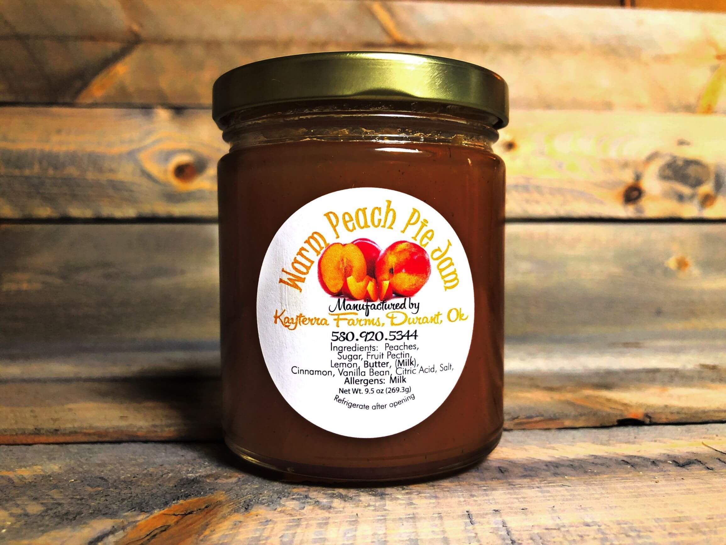 A jar of Warm Peach Pie Jam filled with luscious peach preserves, showcasing a rich golden color with hints of cinnamon and vanilla.