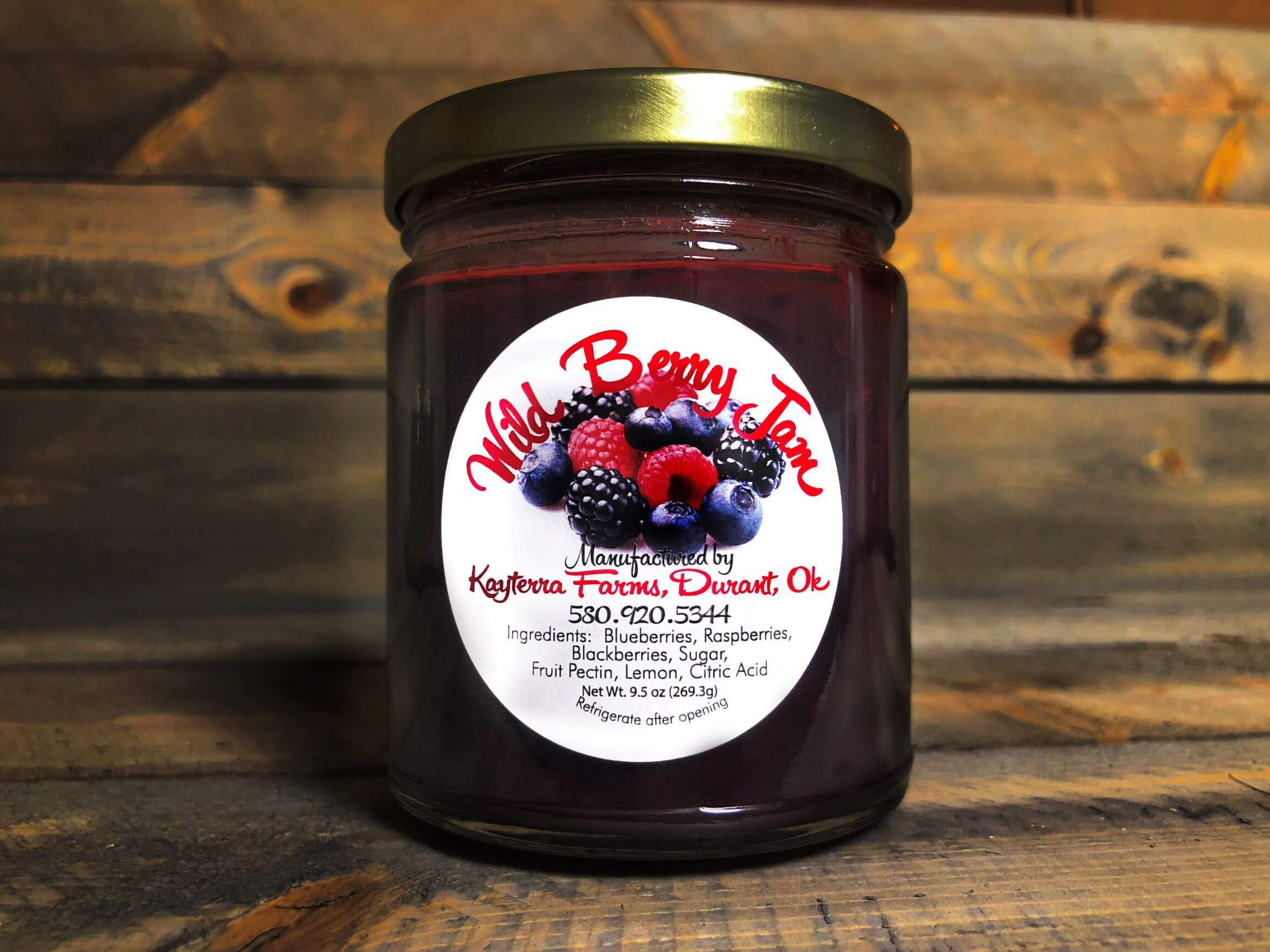 A jar of Wild Berry Jam filled with a vibrant mix of blueberries, raspberries, and blackberries, showcasing its rich purple color.