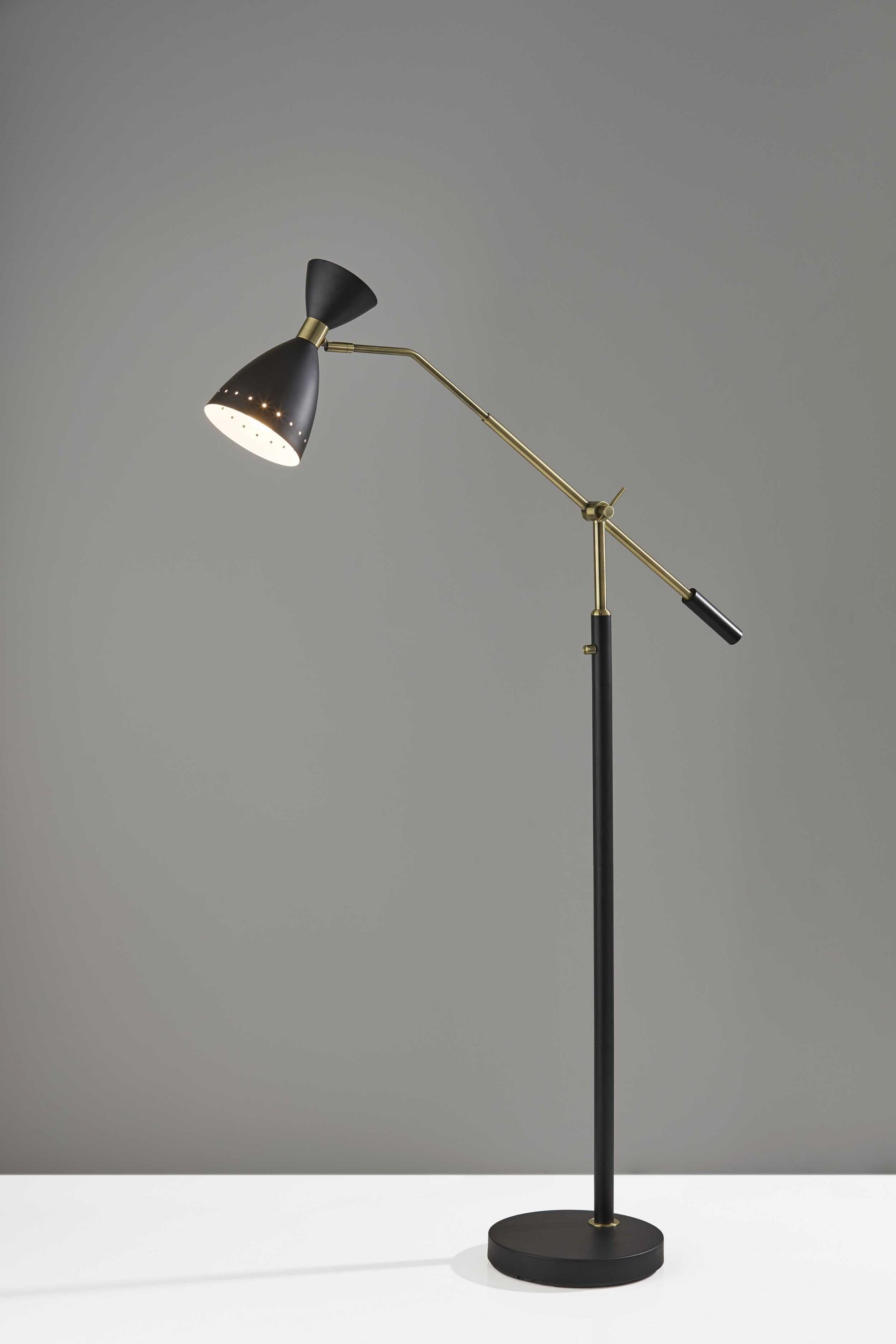 A stylish black metal adjustable floor lamp with an oversized shade and antique brass accents, perfect for modern decor.