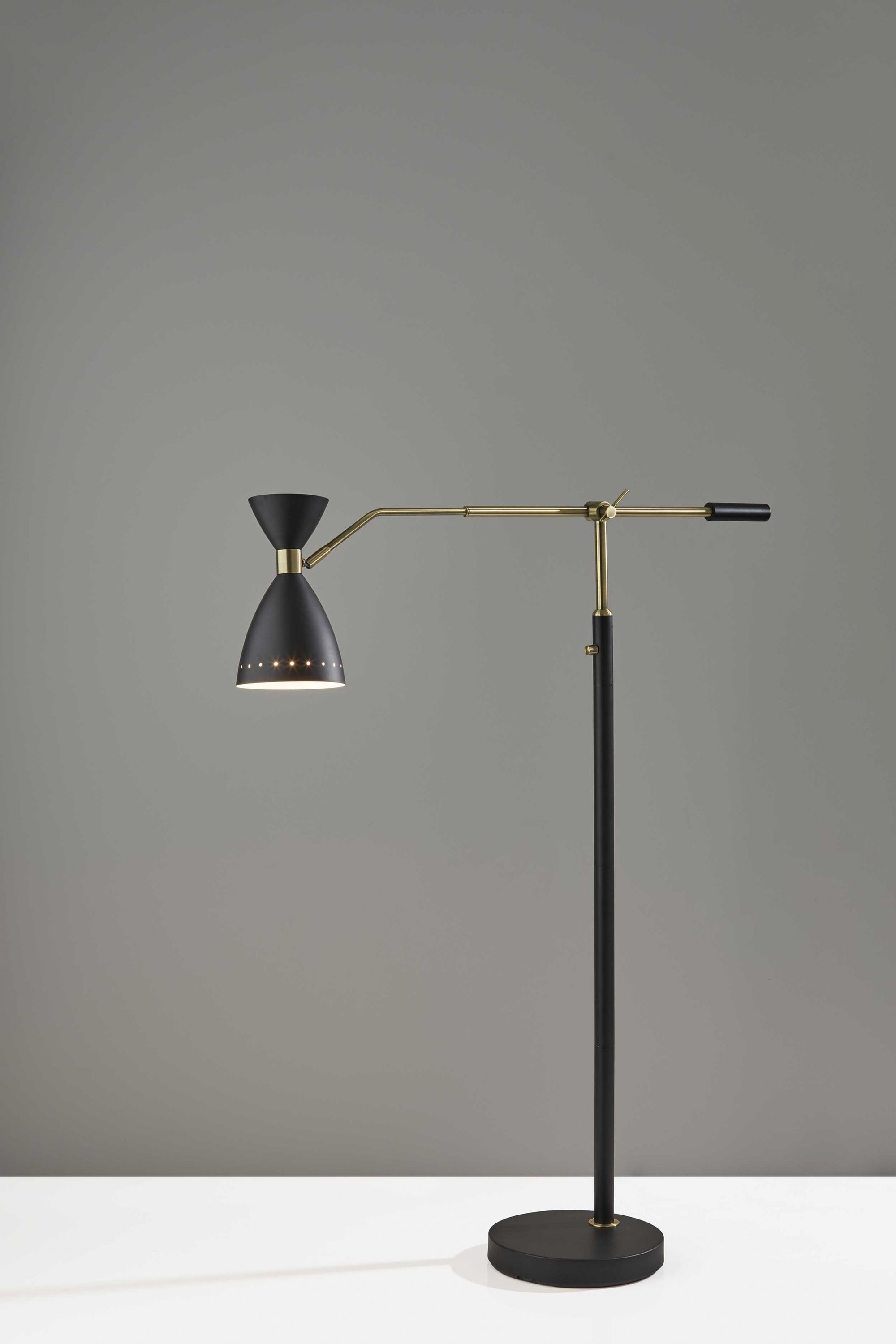 A stylish black metal adjustable floor lamp with an oversized shade and antique brass accents, perfect for modern decor.