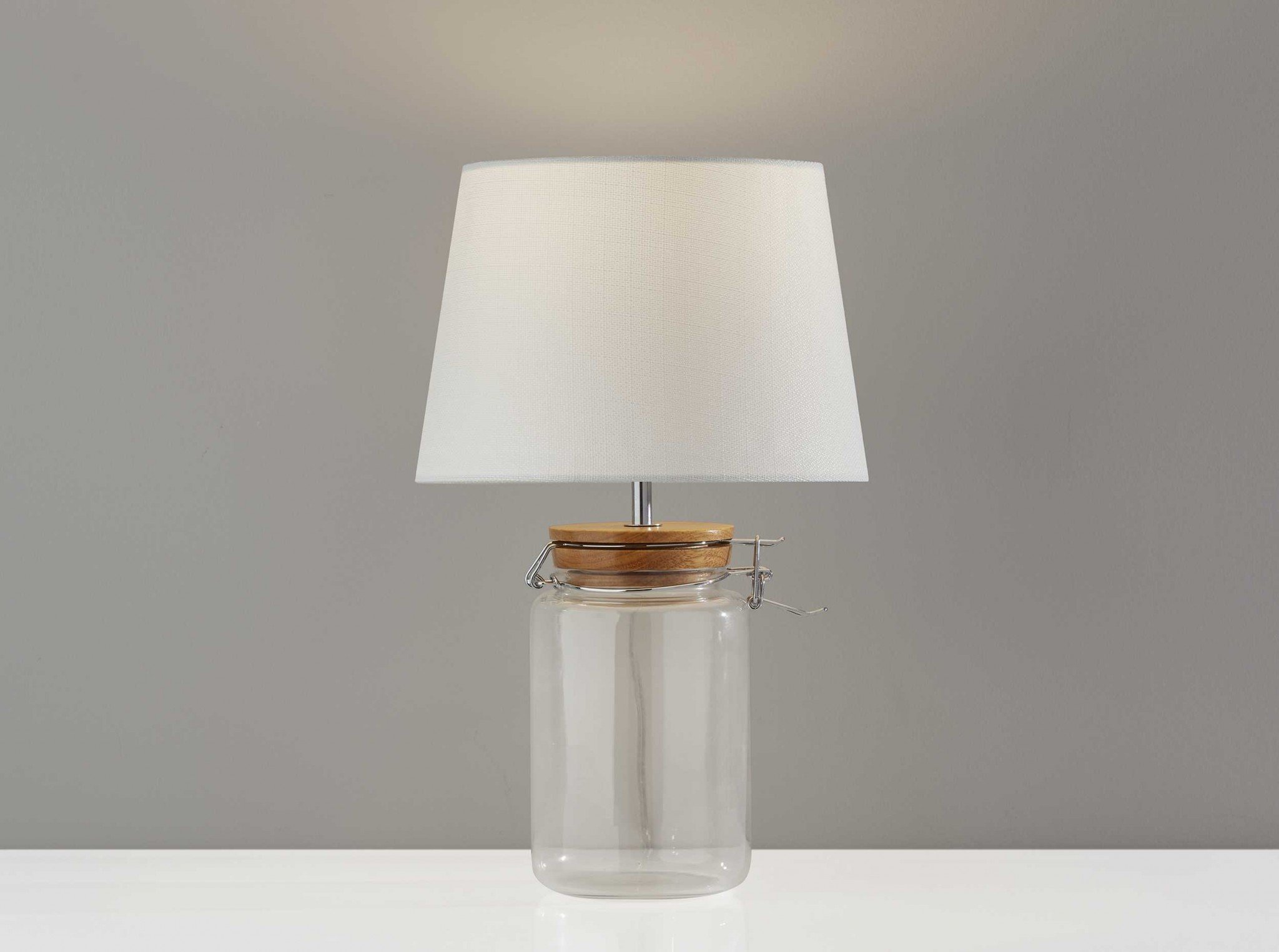 A stylish 10" x 10" x 16" clear jar table lamp featuring a vintage mason jar design with a natural wood top and metal latch lid.