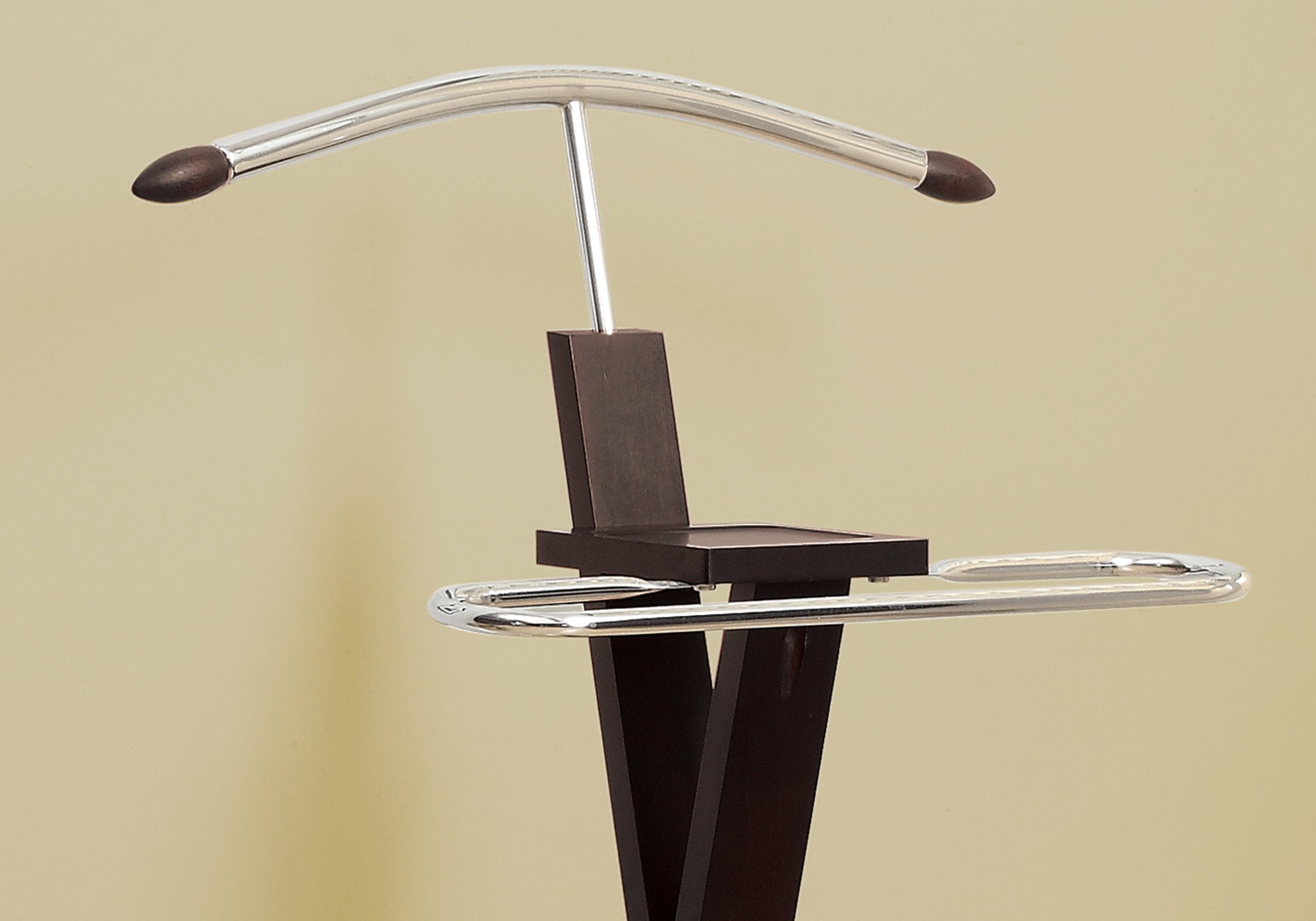 Cappuccino solid wood valet stand with chrome accents, featuring a hanger, accessory tray, and trouser bar, elegantly displayed in a dressing room.