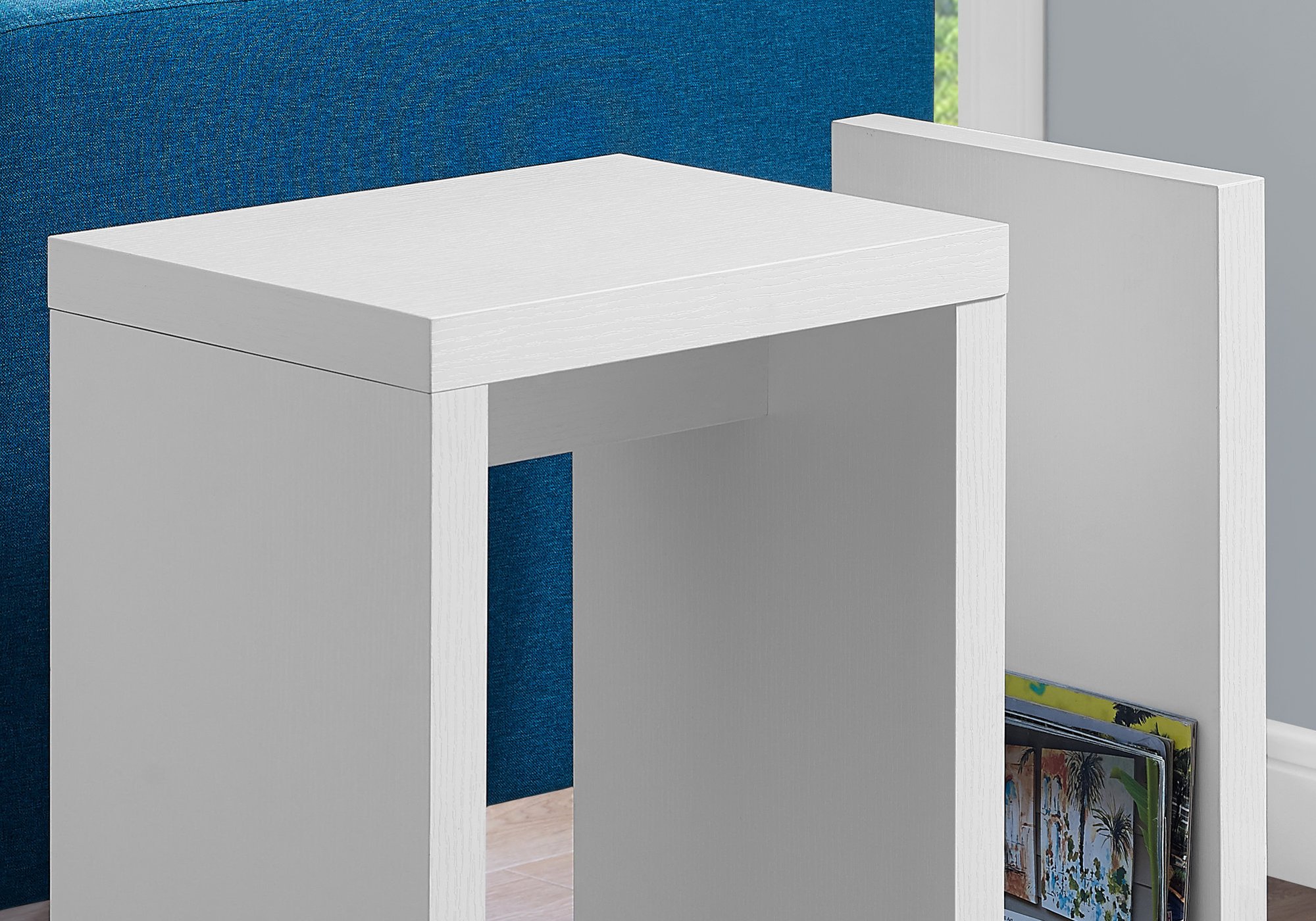 A modern white accent table with thick panels and an open storage slot, perfect for books and magazines.