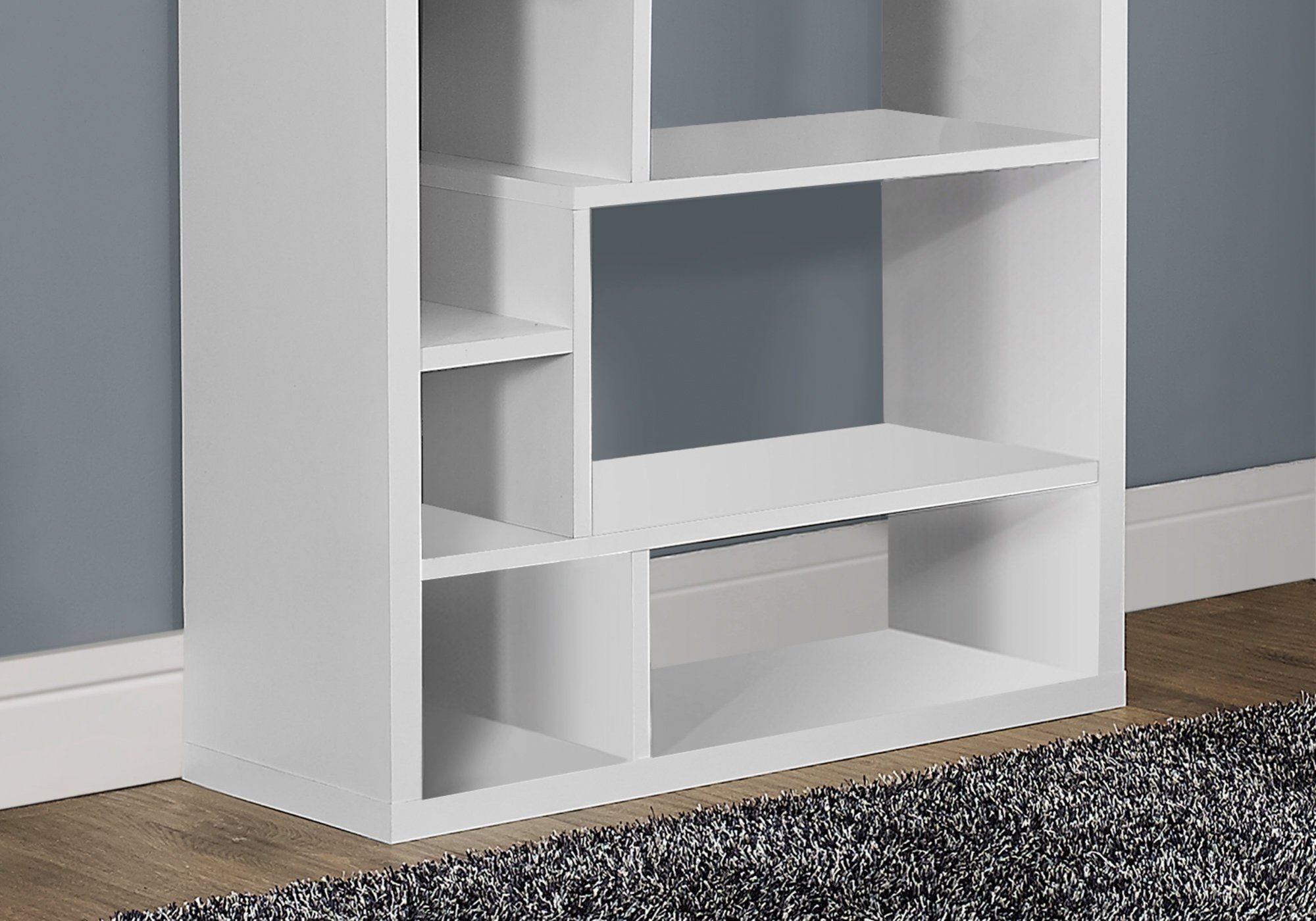 A stylish white particle board bookcase with 14 asymmetrical shelves, designed for modern living spaces.