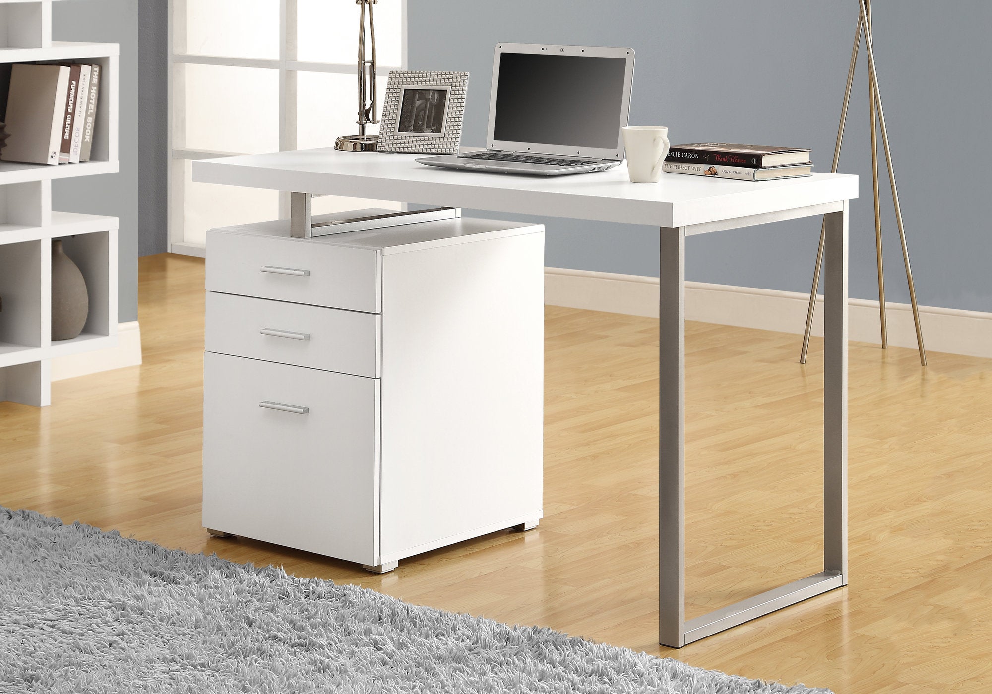 A modern white and silver particle board computer desk with three drawers, showcasing a sleek design suitable for home or office use.