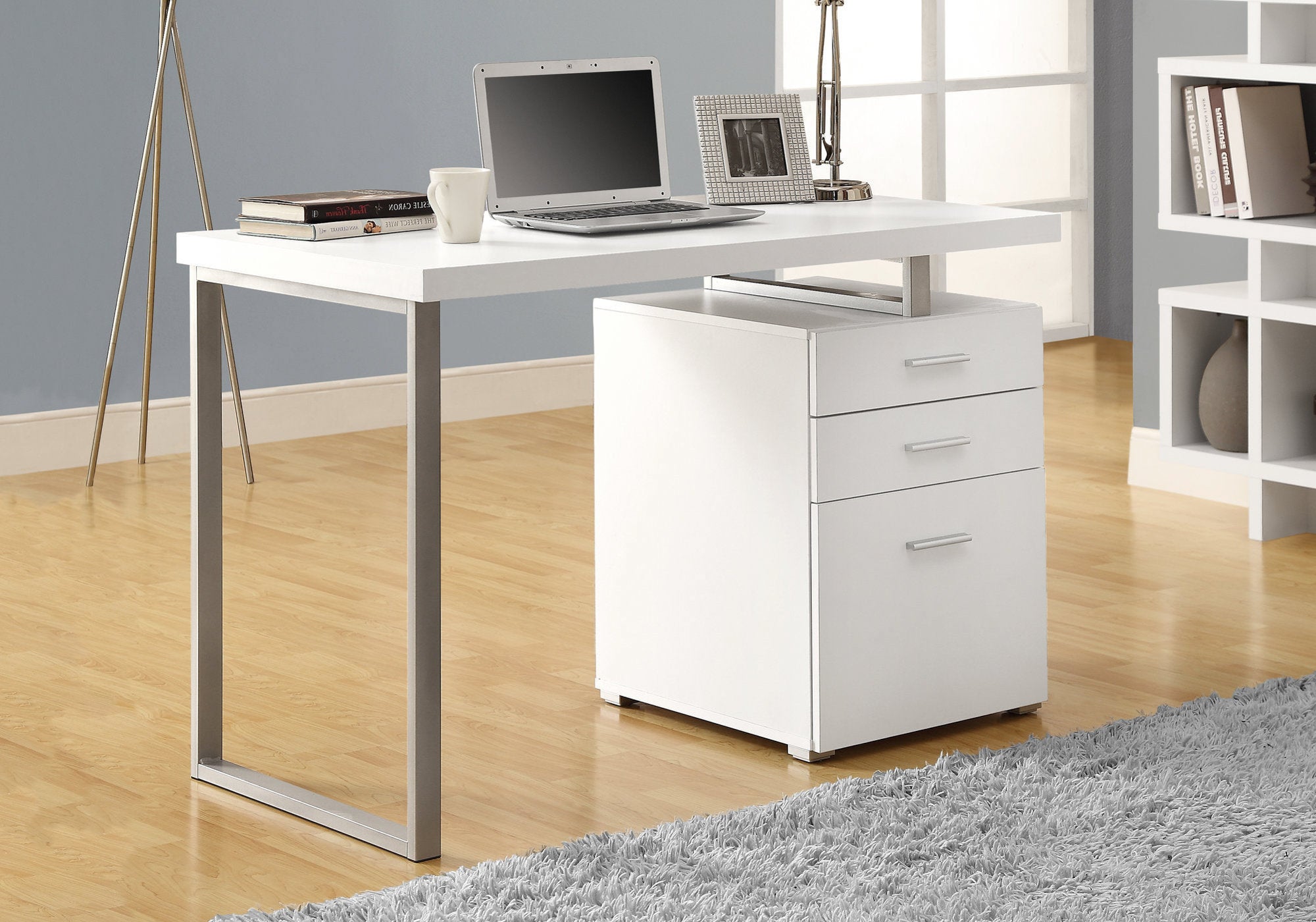 A modern white and silver particle board computer desk with three drawers, showcasing a sleek design suitable for home or office use.