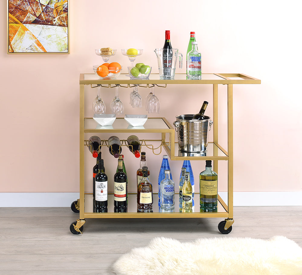 Elegant gold and clear glass serving cart with three shelves and caster wheels, perfect for serving meals and drinks.