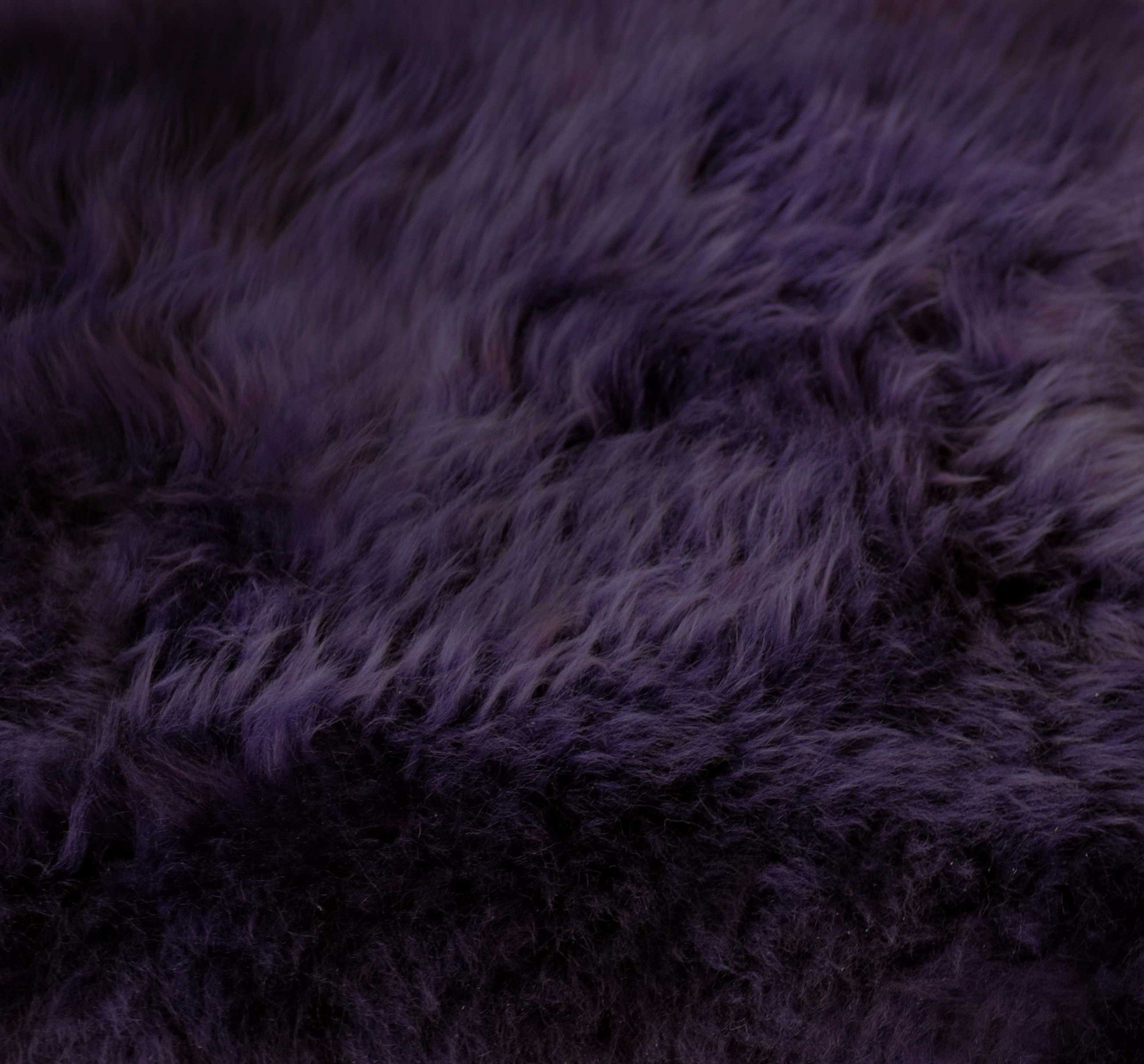 A luxurious 2x3 inches purple New Zealand natural sheepskin rug showcasing its rich texture and deep plum color, perfect for home decor.