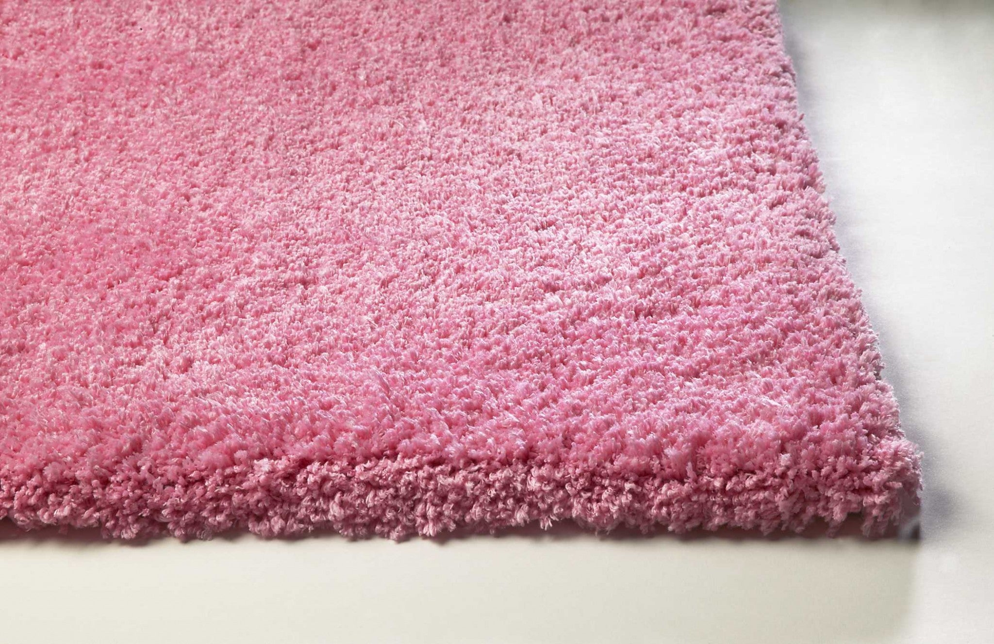 A vibrant hot pink indoor shag rug, hand woven with high-grade polyester and cotton backing, perfect for adding color and comfort to any room.