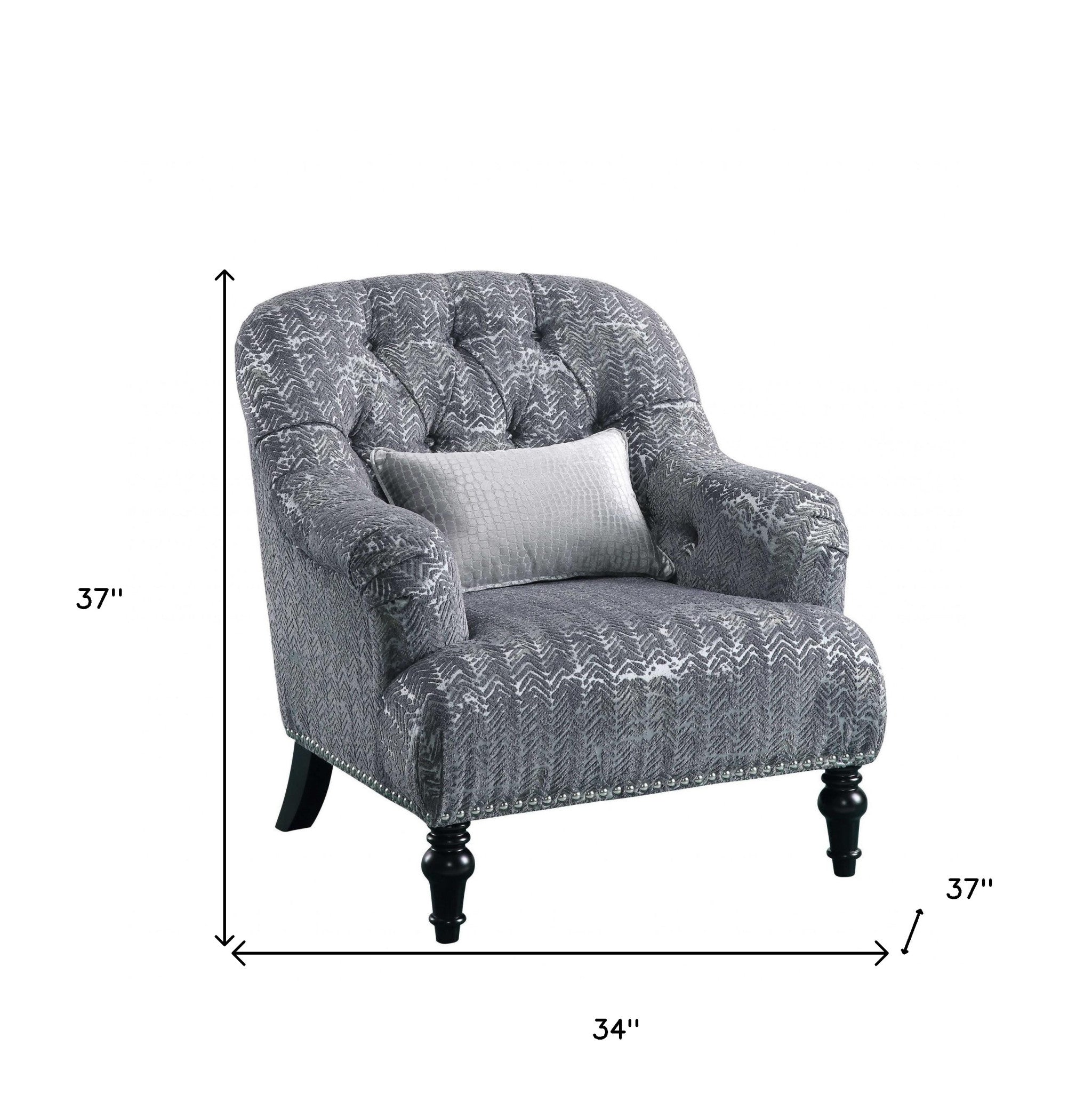 A stylish gray patterned velvet chair with a plush pillow, featuring button tufted back and arms, resting on black wood bun-turned legs.