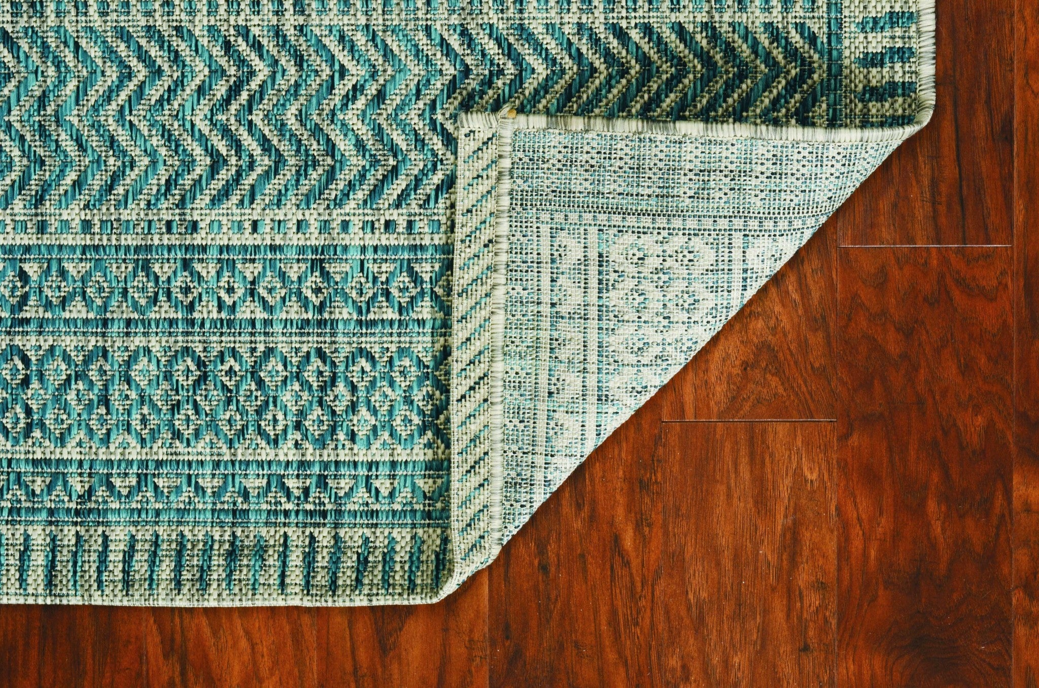 Teal tribal indoor outdoor rug, machine woven, UV treated, showcasing vibrant colors and patterns, perfect for enhancing any space.