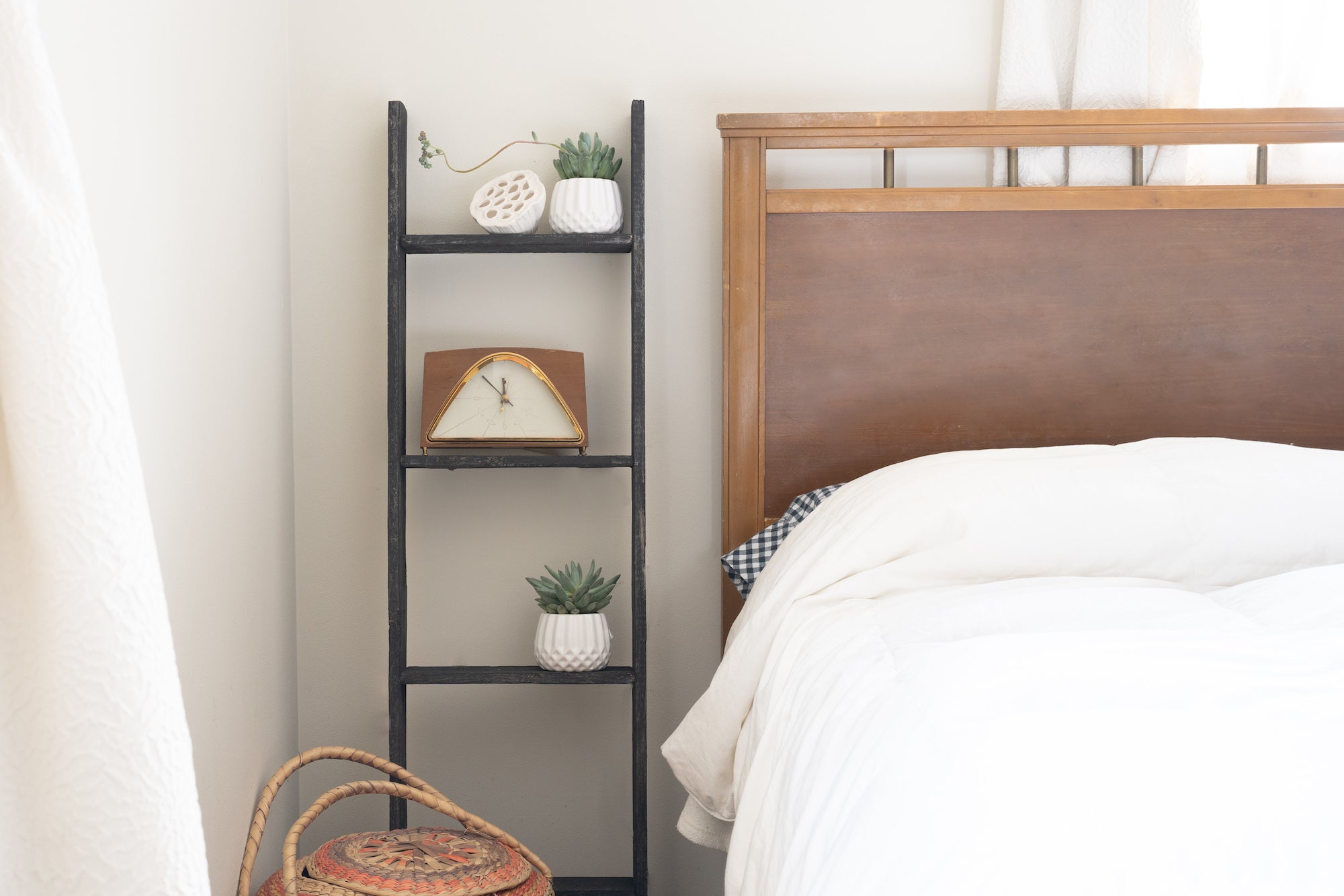 A rustic black wood ladder shelf with four steps, showcasing its unique handcrafted design and reclaimed wood texture.