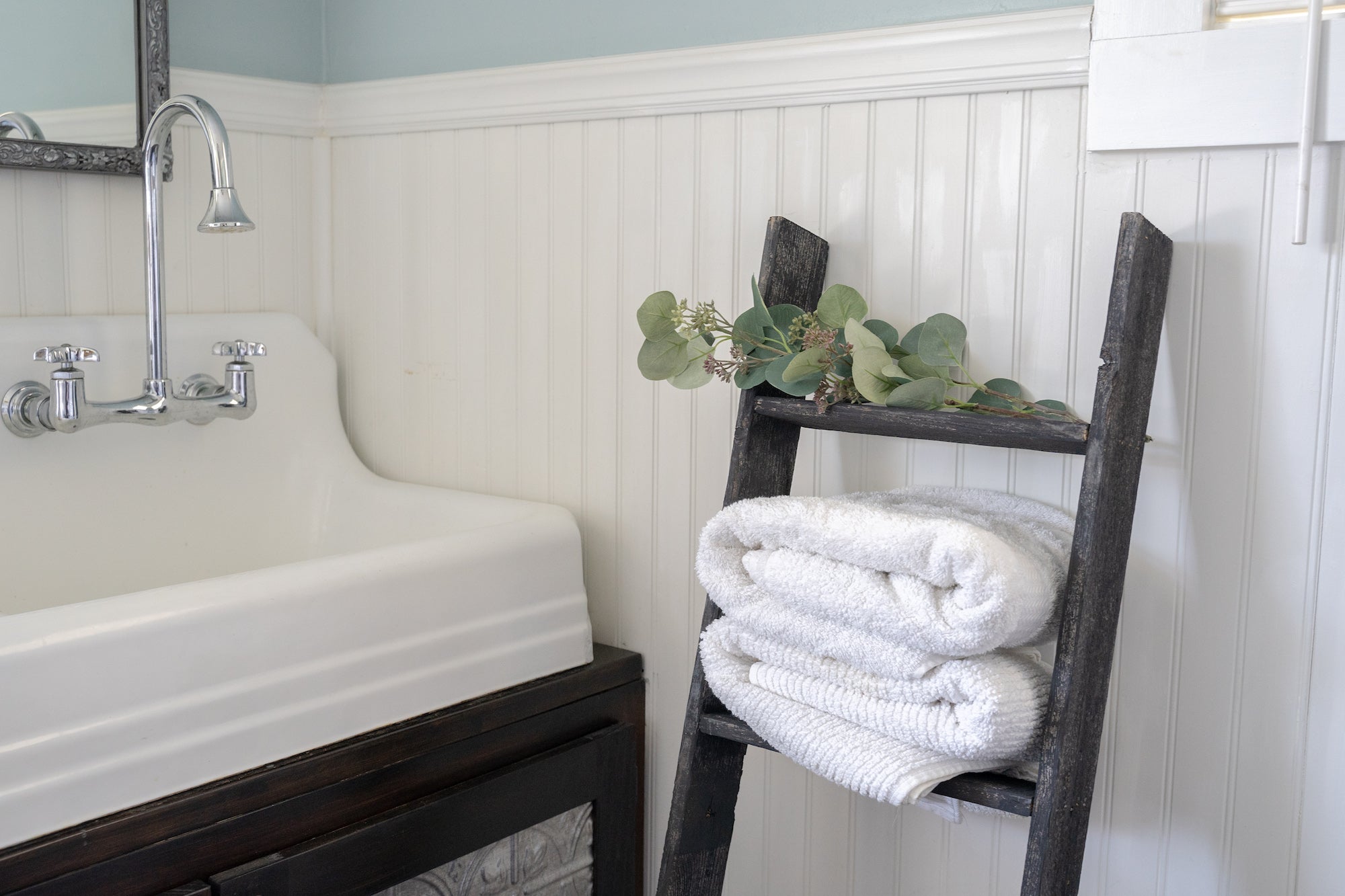 A rustic black wood ladder shelf with four steps, showcasing its unique handcrafted design and reclaimed wood texture.