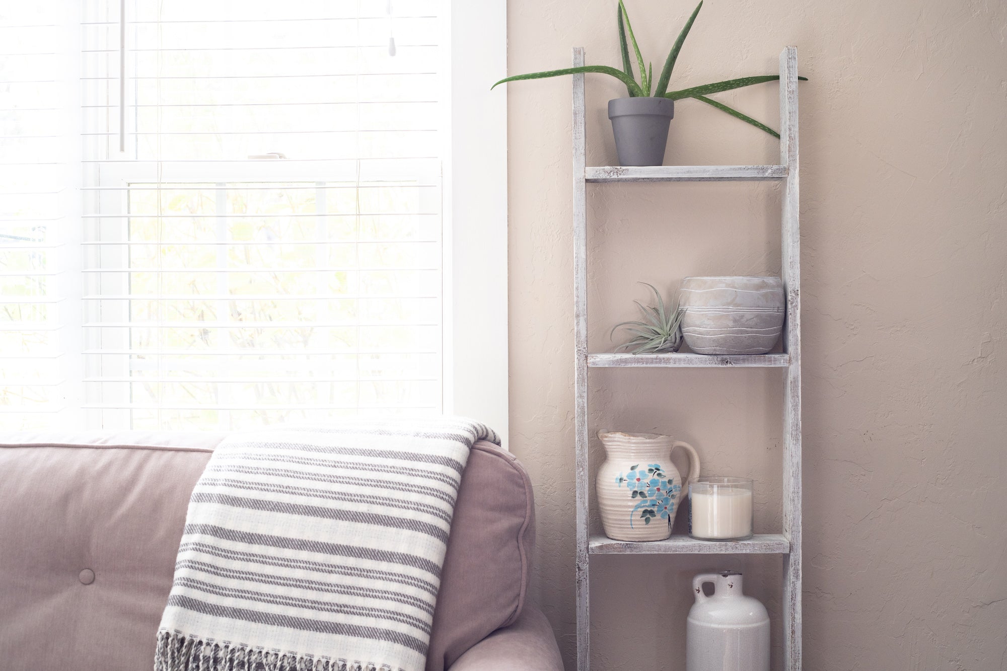 A rustic white wood ladder shelf with four steps, showcasing its unique handmade craftsmanship and reclaimed wood design.