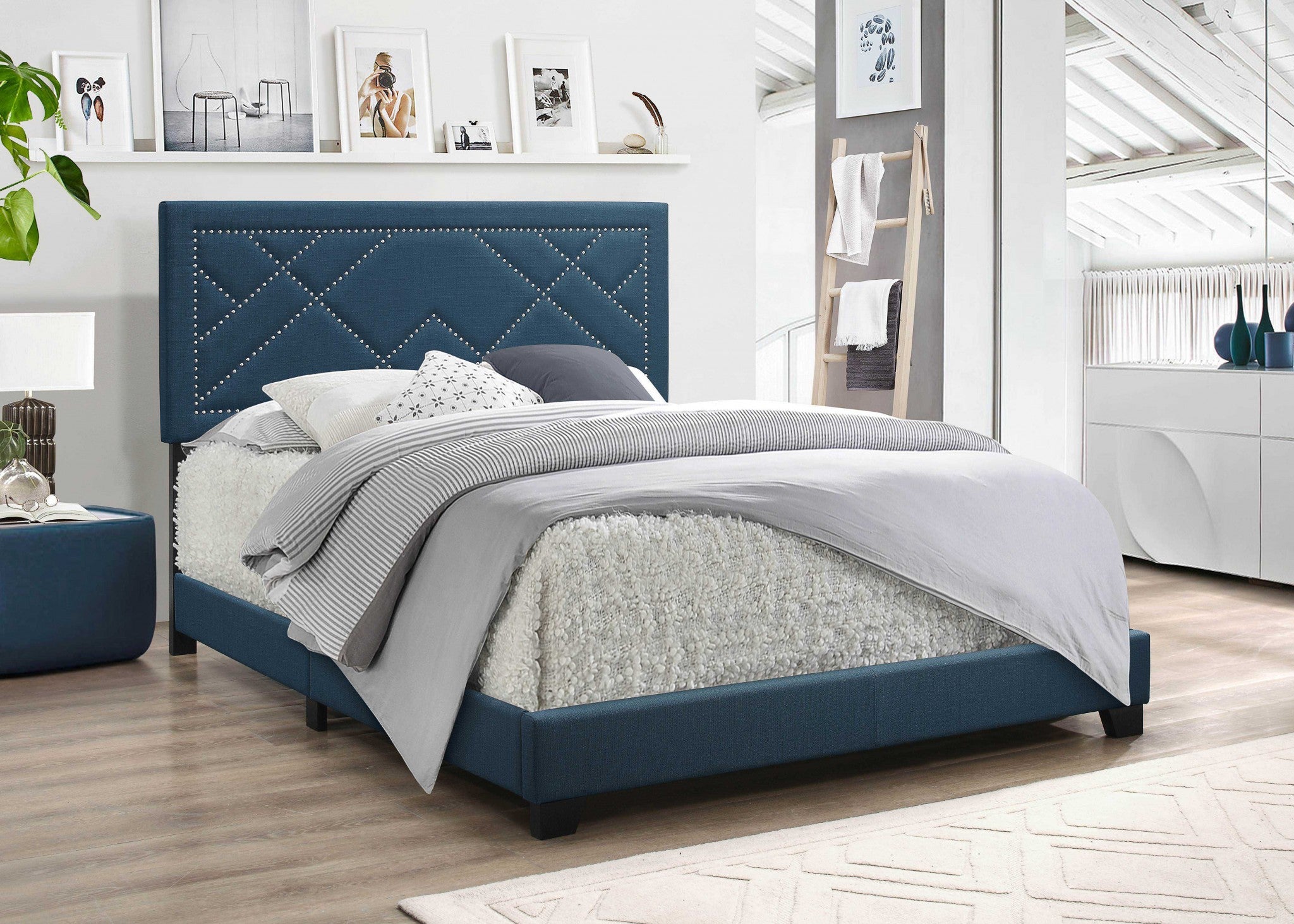 A dark teal fabric upholstered bed featuring a padded headboard with chrome nailhead trim and a low-profile footboard, set in a stylish bedroom.