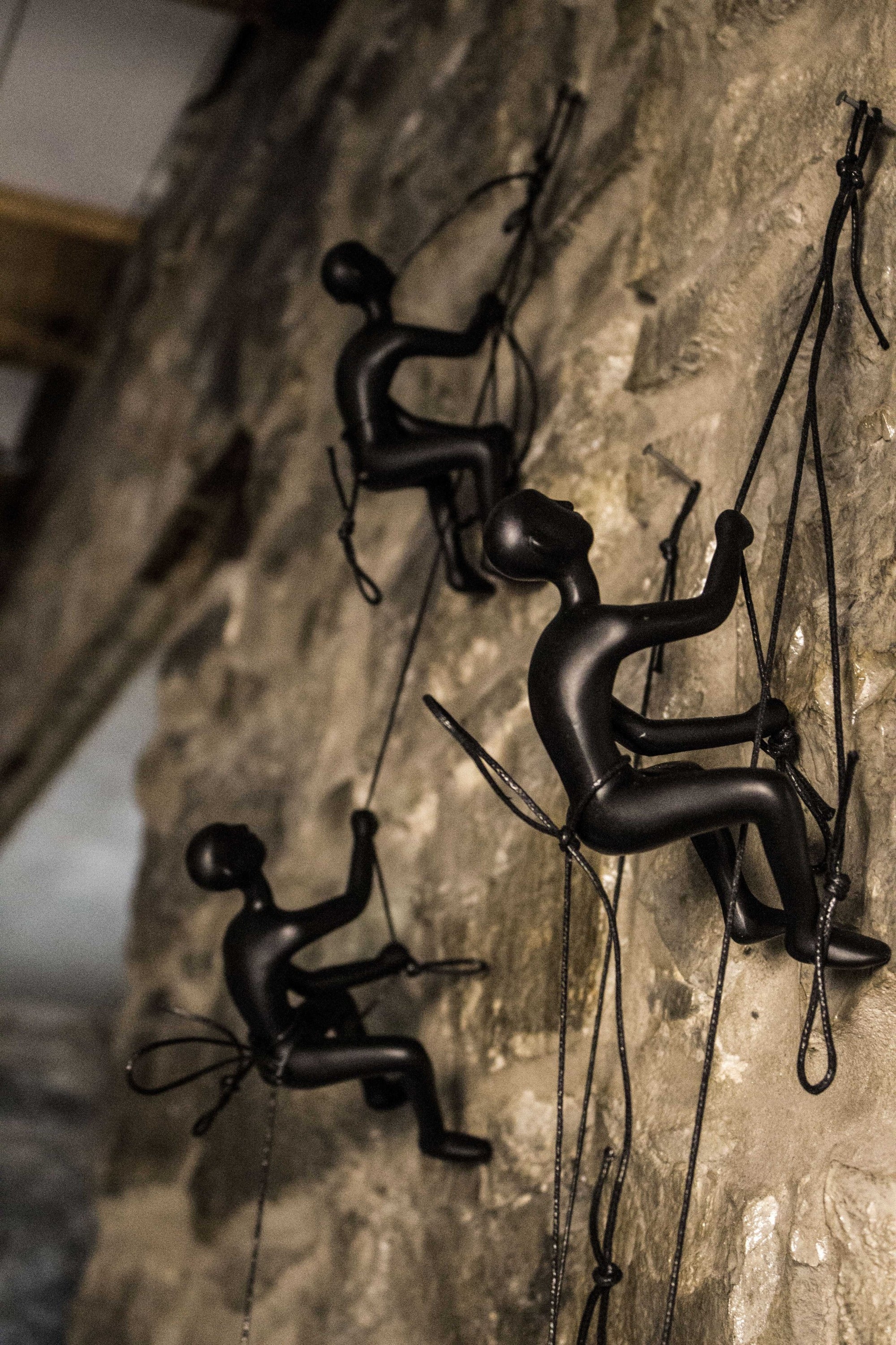 A striking black resin sculpture of a man climbing, designed for wall art display, showcasing modern decor style.