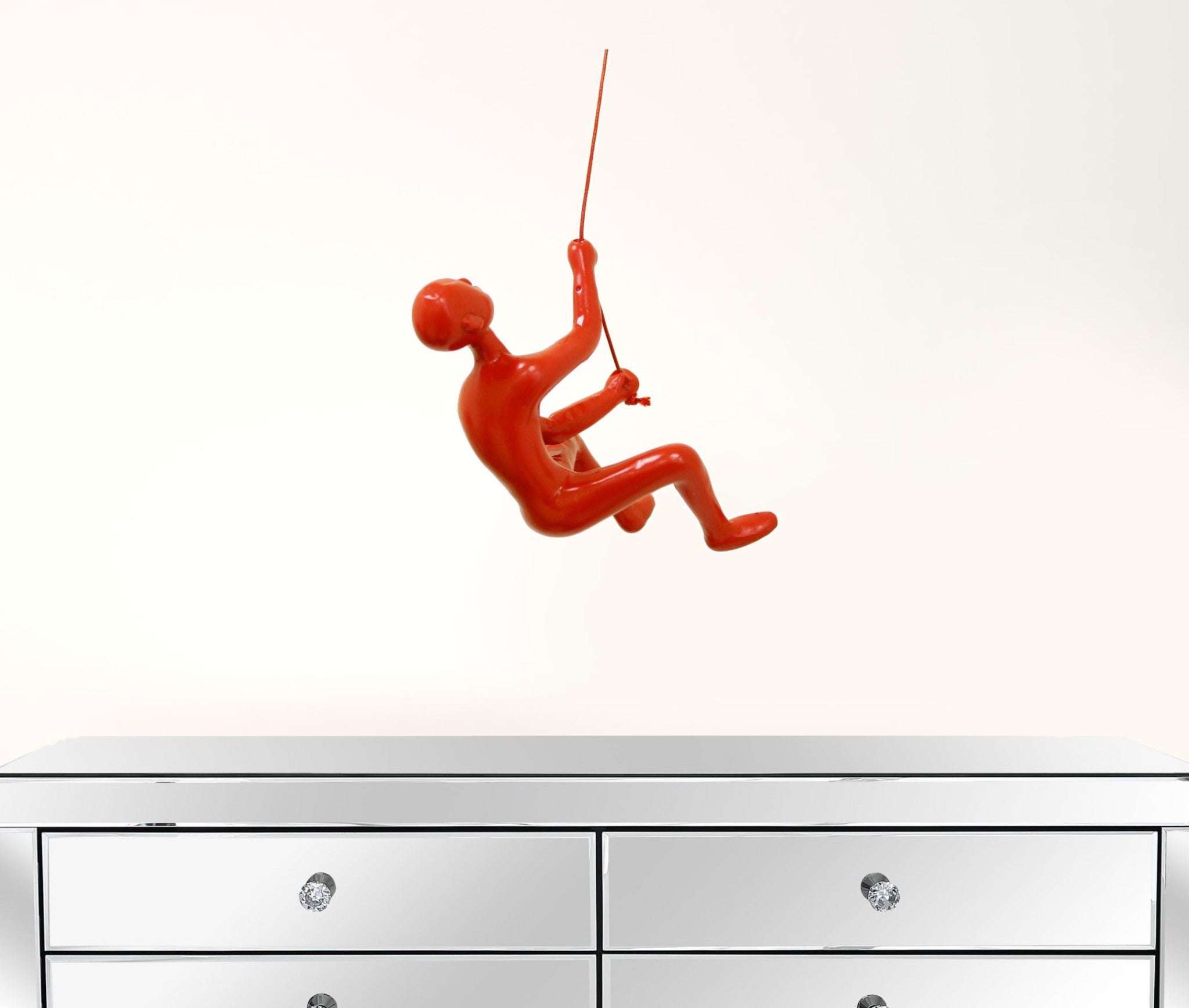 A vibrant red resin sculpture of a man climbing, showcasing a unique three-dimensional design for wall decor.