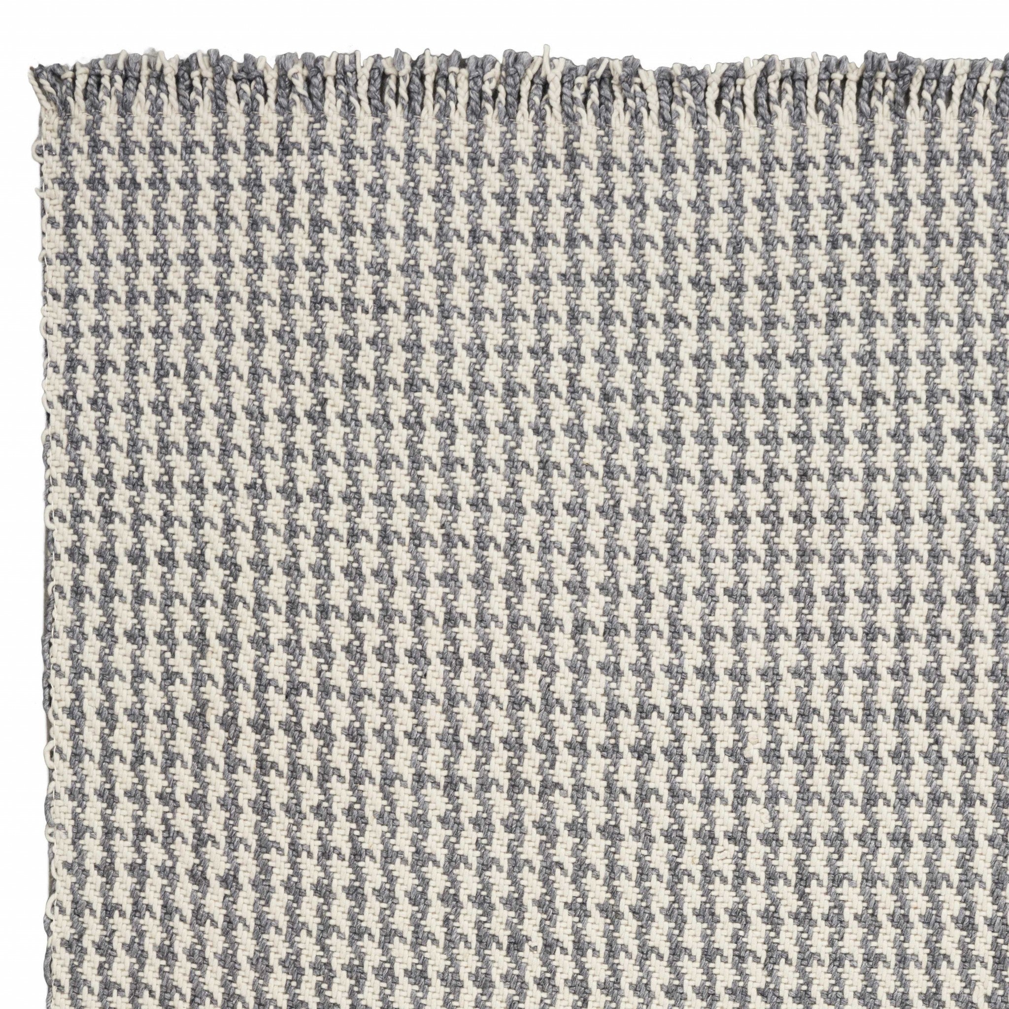 A luxurious 7x9 inches wool area rug in ivory and grey houndstooth pattern, featuring braided fringe for a modern touch.