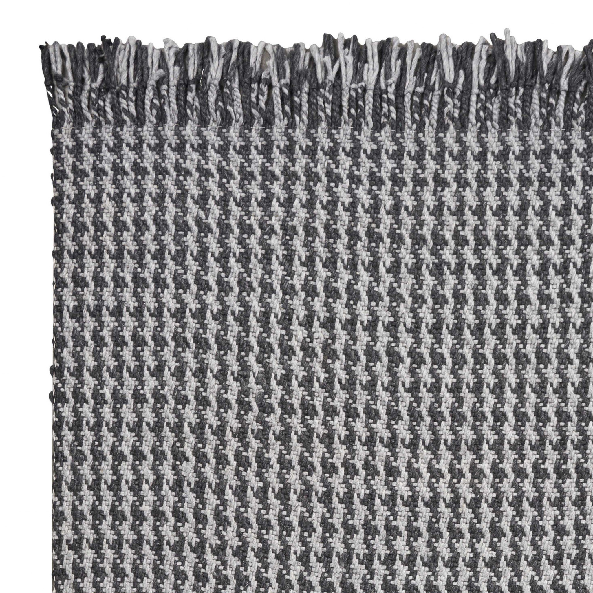 A beautifully crafted 8x10 grey hand woven houndstooth indoor area rug featuring a modern design and braided fringe, perfect for enhancing home decor.